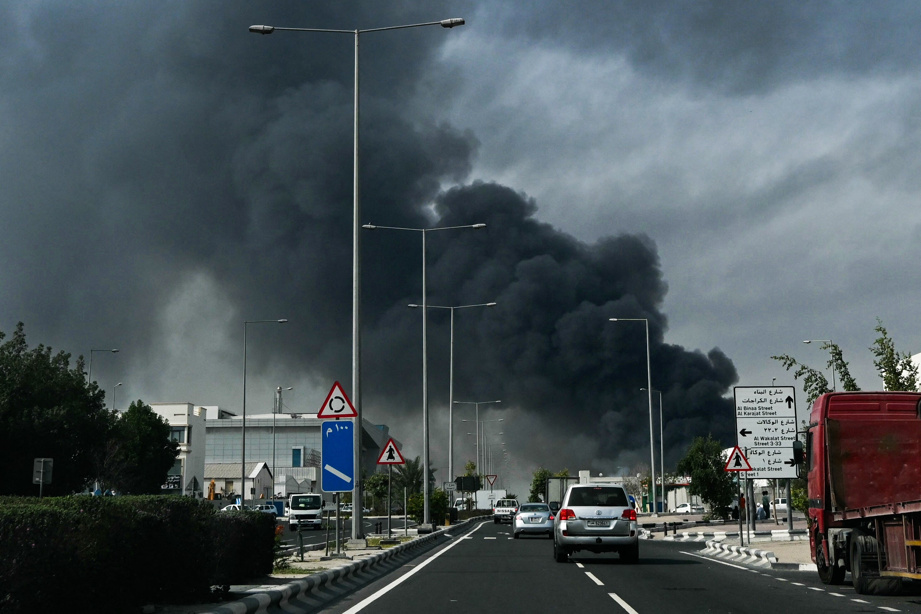 Motorists drive past a plume of smoke rising from a reported Iranian strike in the industrial district of Doha on March 1, 2026.