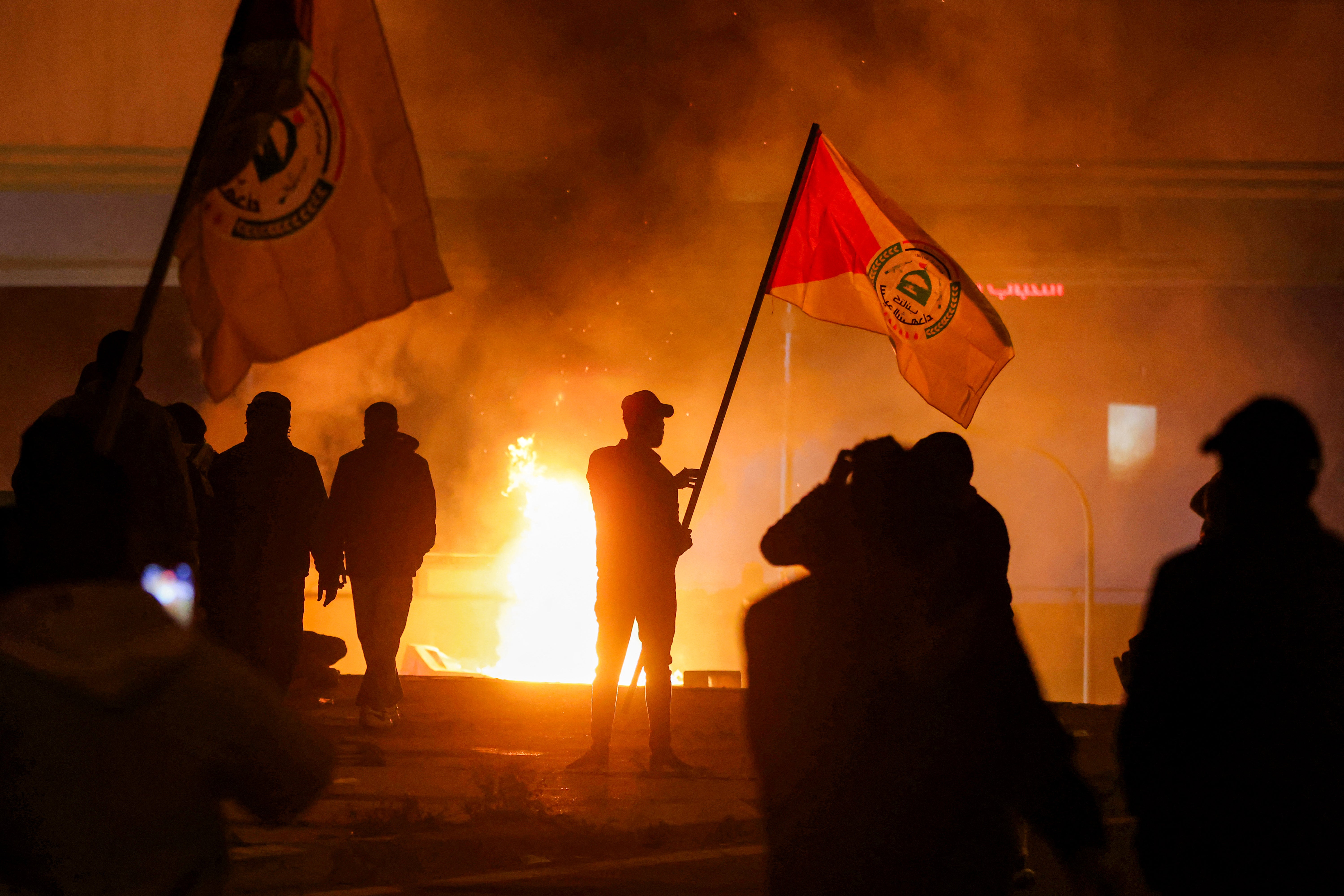 Protesters stand near a fire during clashes with Iraqi security forces as they try to approach a bridge leading to the Green Zone where the US embassy is located in Baghdad on 1 March 2026