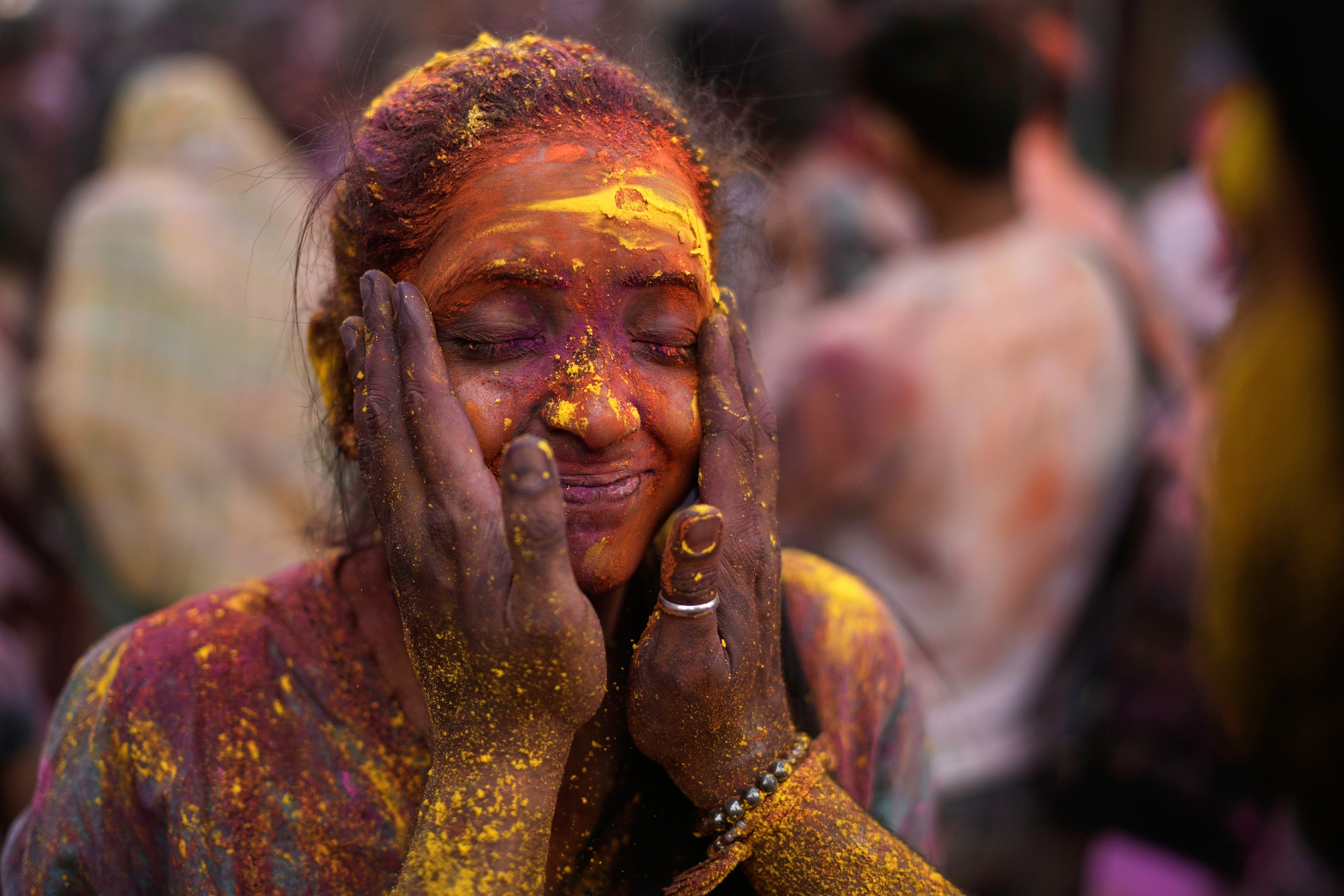 A woman has her face smeared with coloured powder as she celebrates Holi in Hyderabad