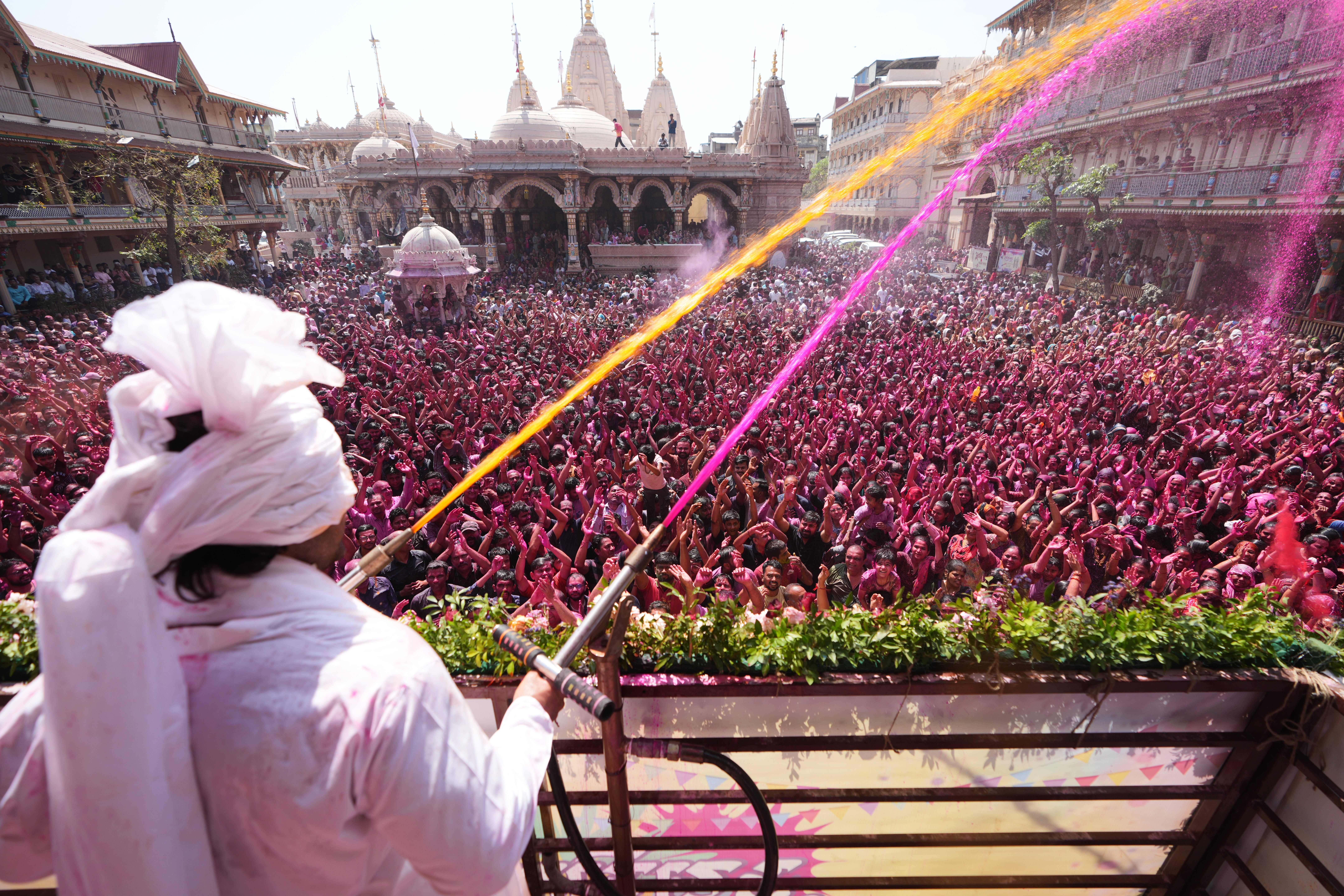 A priest sprays coloured water on devotees during a celebration of Holi at the Kalupur Swaminarayan Temple in Ahmedabad on 4 March 2026