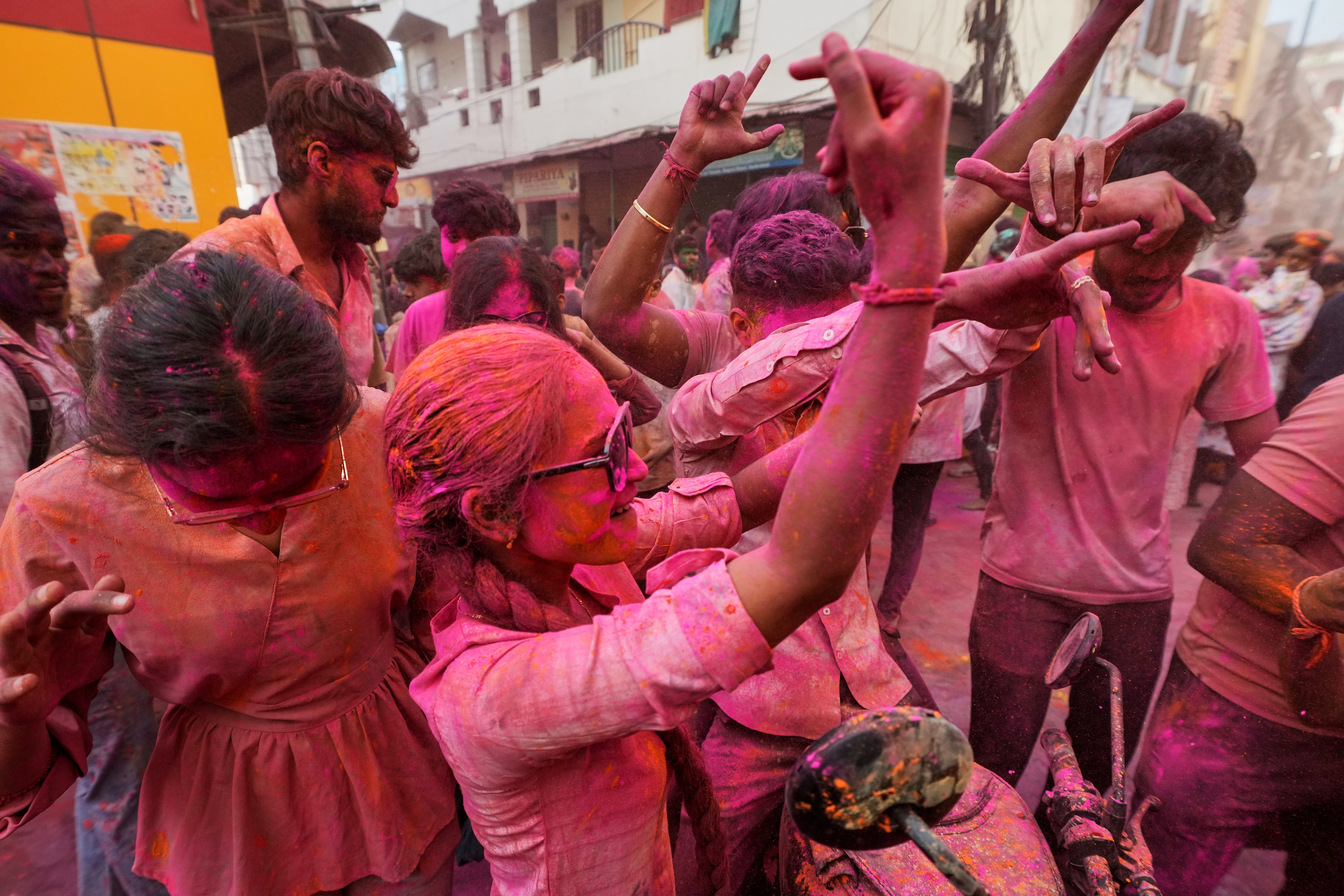 People smeared with coloured powder dance during a Holi celebration in Hyderabad