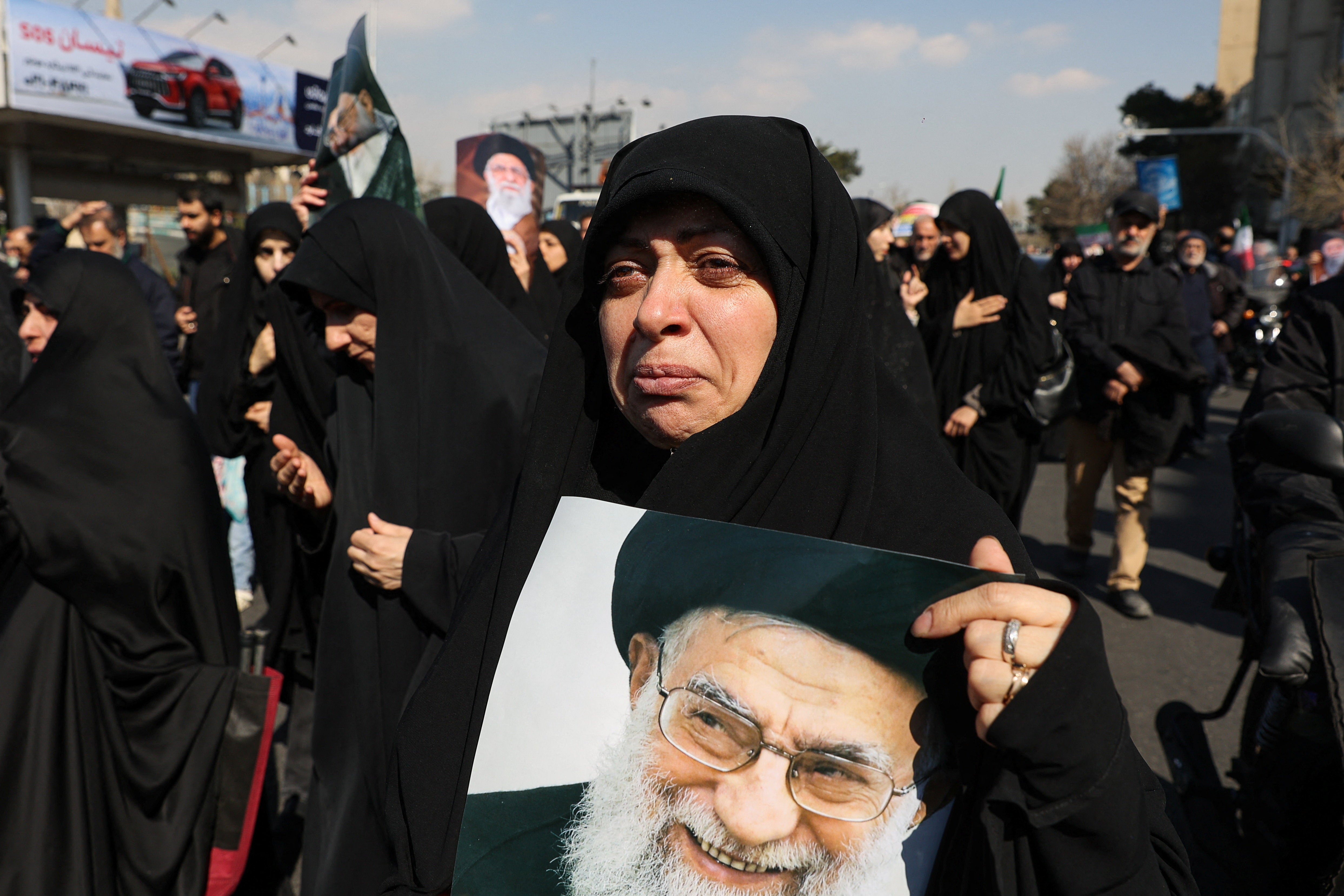 A demonstrator reacts while holding an image of Iran's late Supreme Leader Ayatollah Ali Khamenei