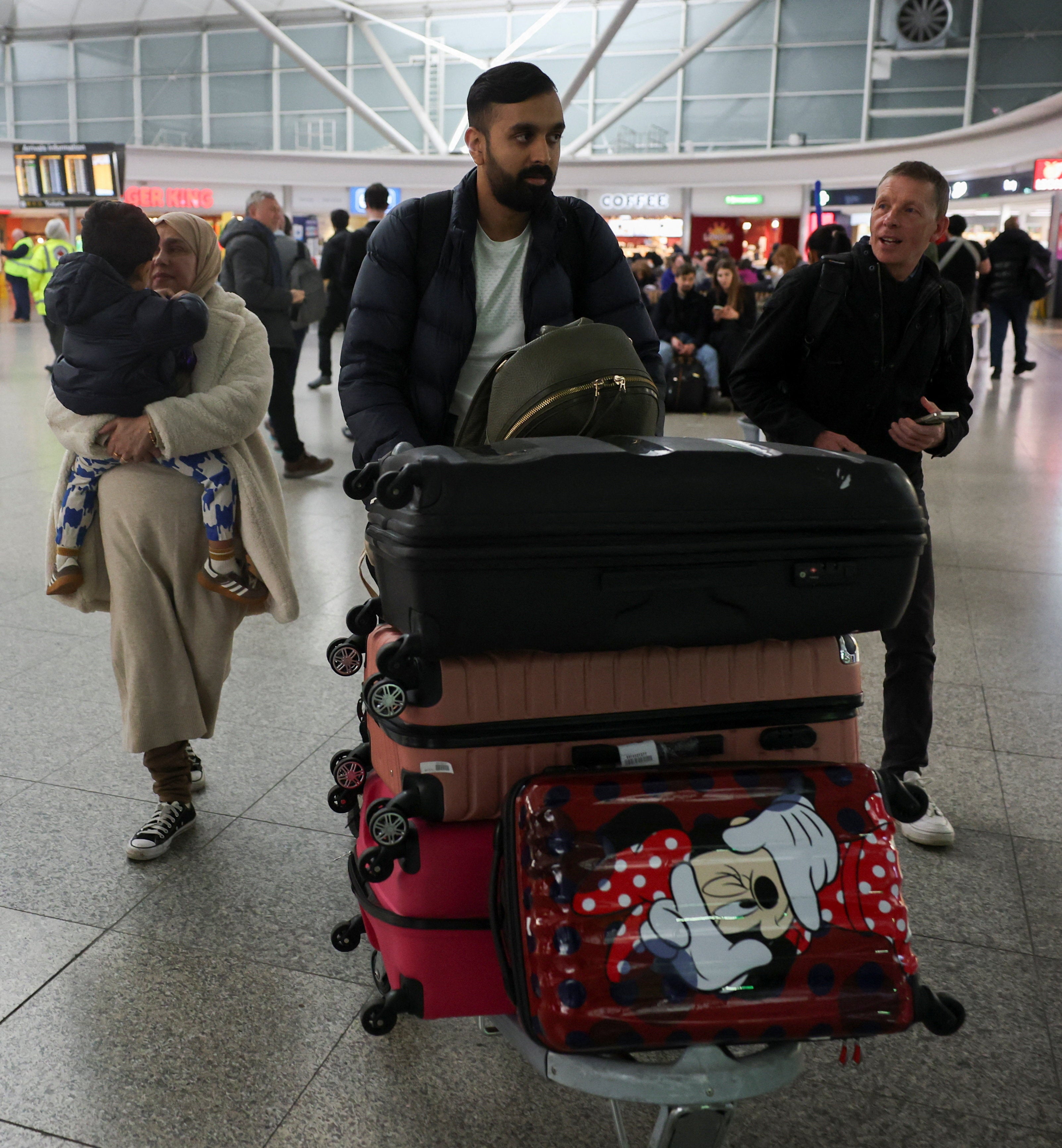 A man walks with luggage, as passengers from the first government-chartered flight for British nationals, which departed from Oman, arrive at London Stansted Airport, amid the US-Israeli conflict with Iran, near London, Britain, 6 March 2026