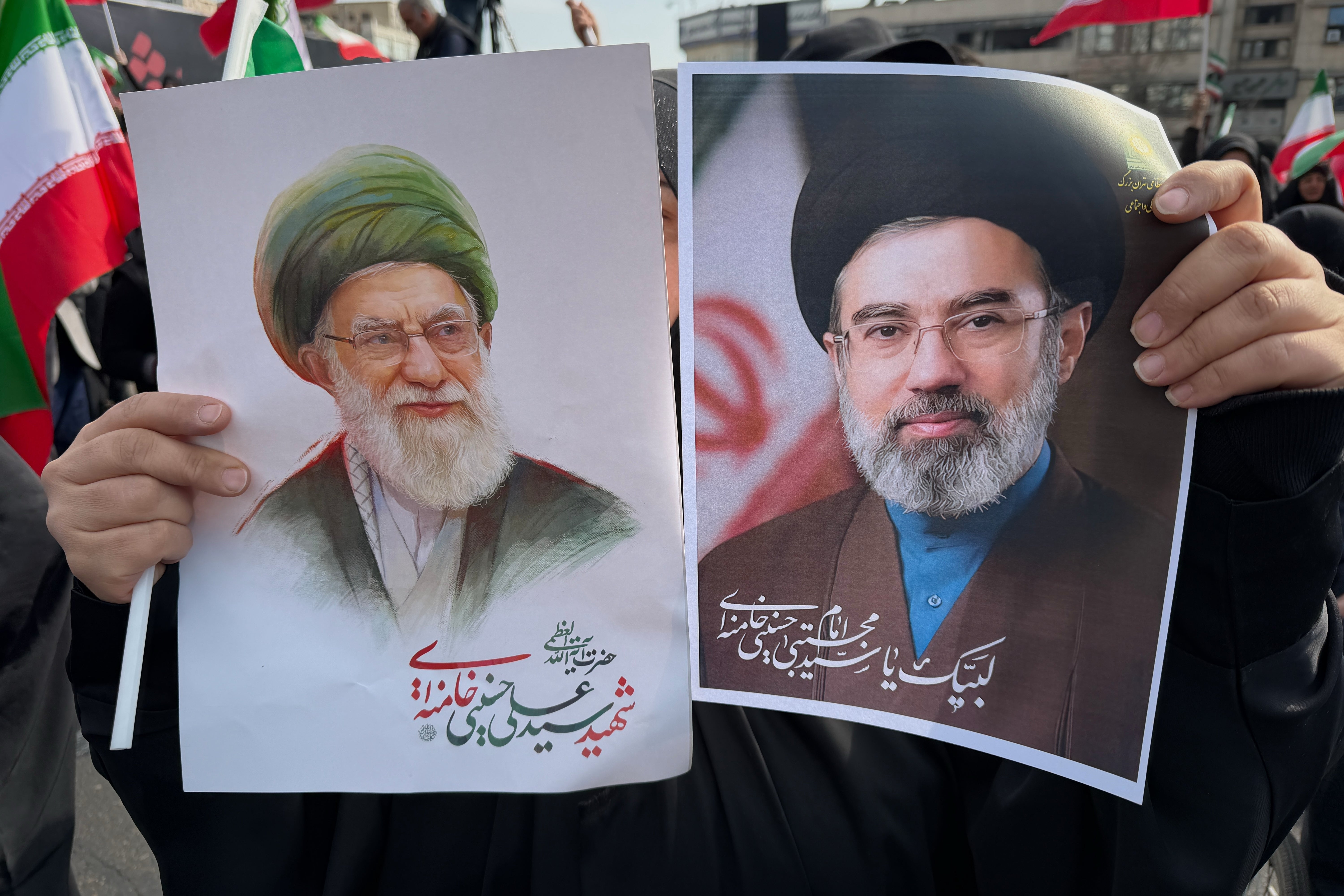 A woman holds posters of Ayatollah Mojtaba Khamenei, right, the successor to his late father, Ayatollah Ali Khamenei, as supreme leader, during a rally supporting him in Tehran, Iran (Vahid Salemi/AP)