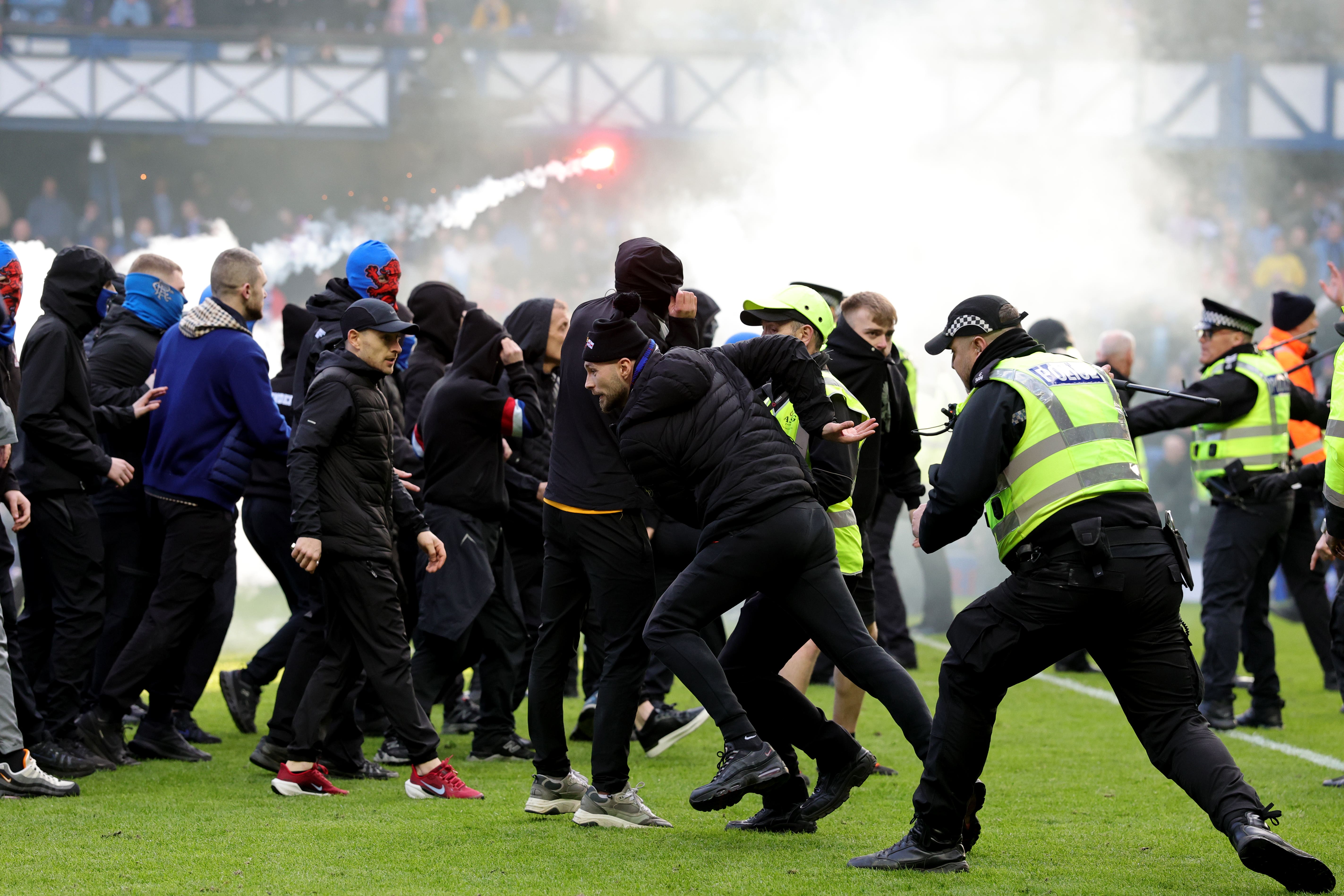 Police and stewards force fans back after they invaded the Ibrox pitch following the Scottish Cup quarter-final between Rangers and Celtic
