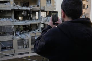 A man takes pictures of a destroyed apartment at a residential building that was hit by an Israeli airstrike in Beirut, Lebanon
