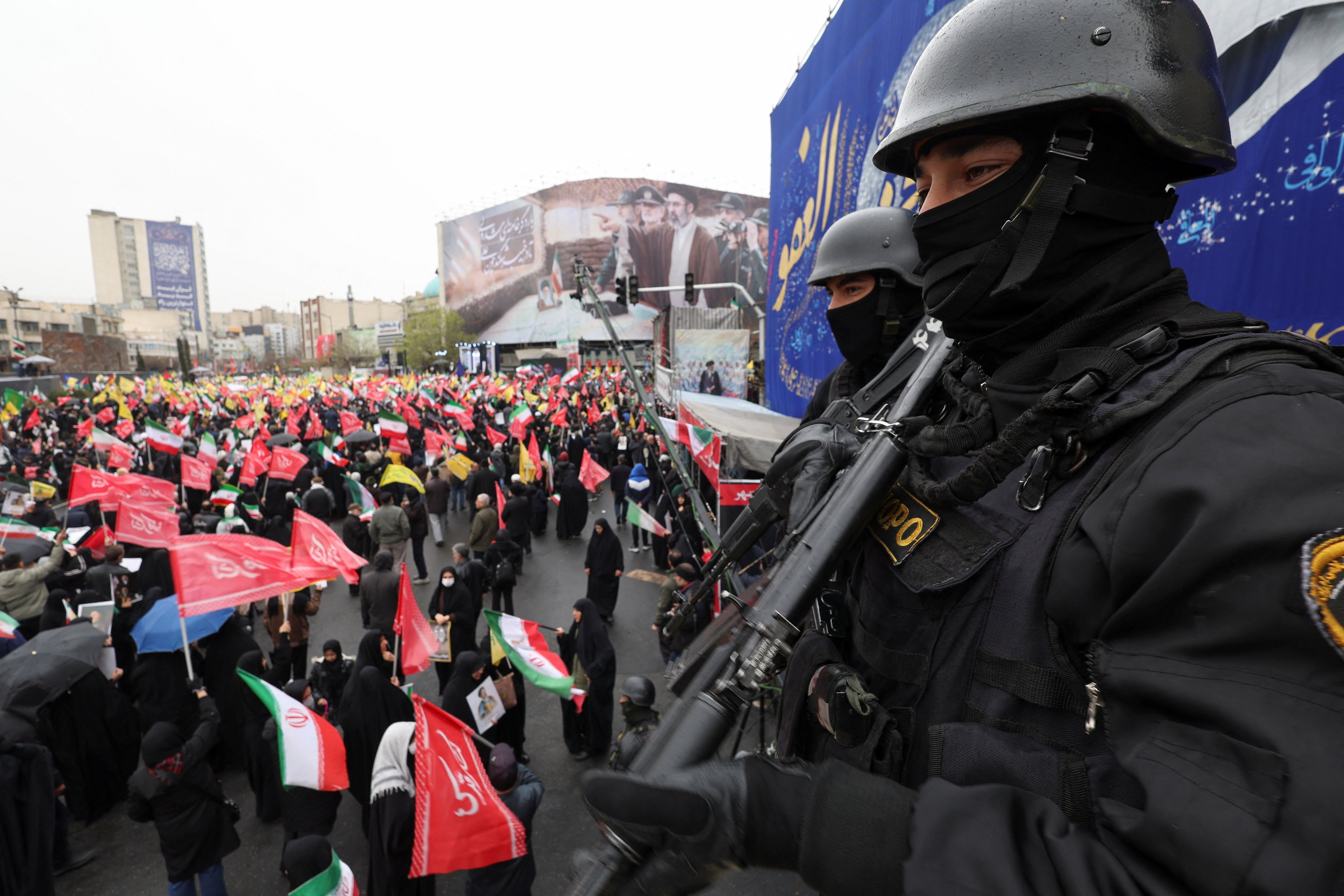 Security personnel stand guard as Iranians take part in a protest marking the annual al-Quds Day