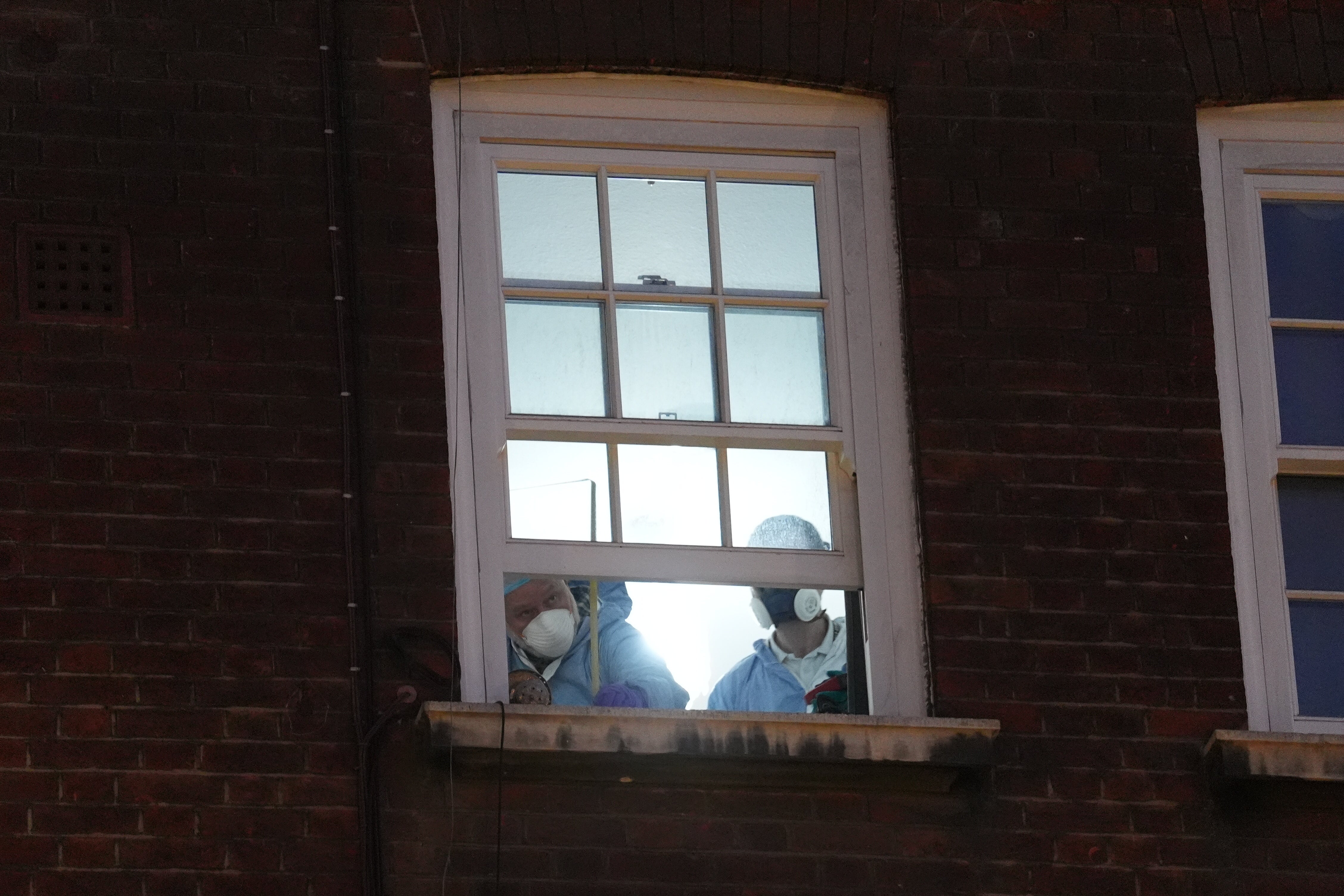A forensic investigator at the window of a property near the junction of Great Peter Street and Horseferry Road in Westminster
