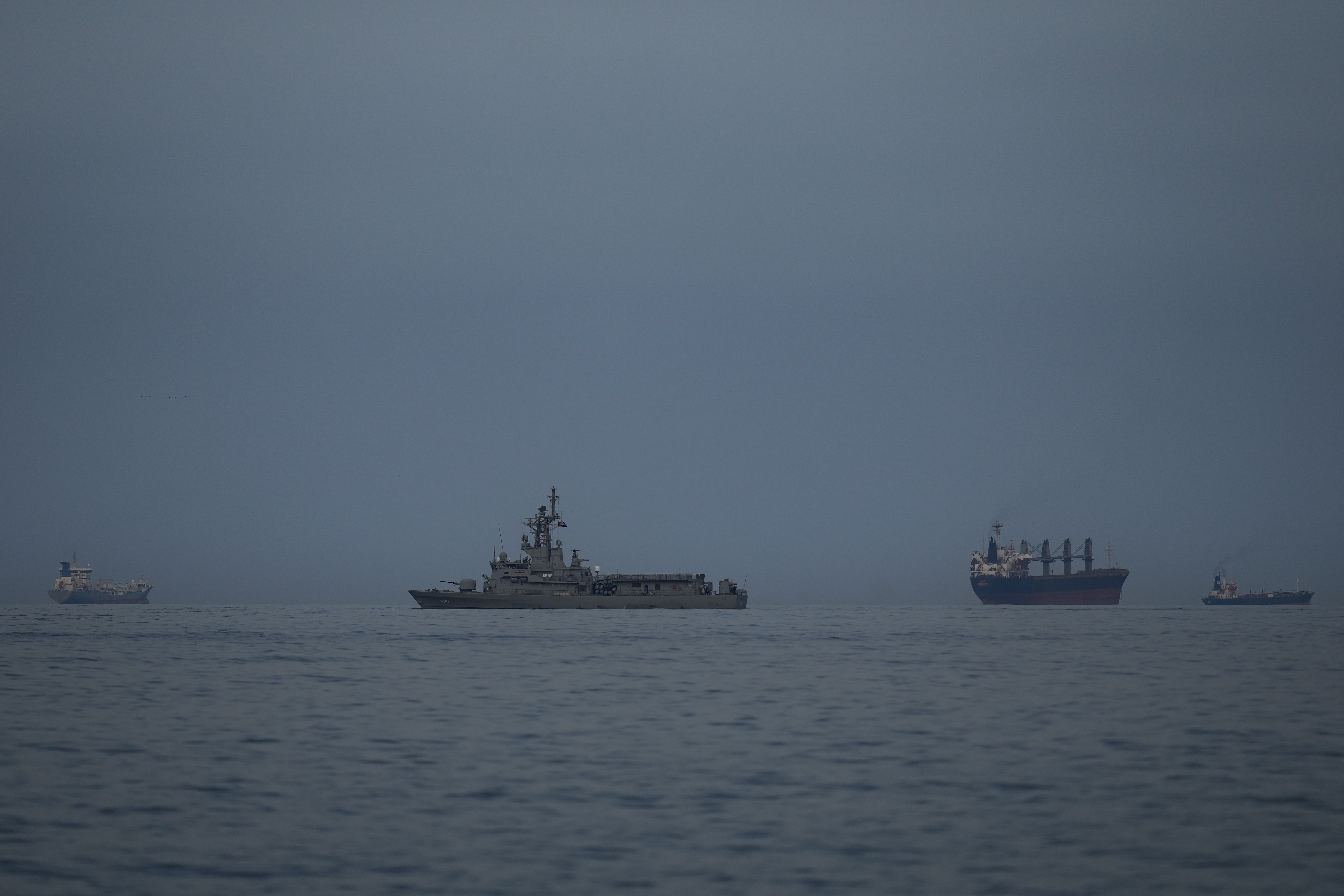 A UAE navy vessel patrols next to stranded cargo ships and oil tankers stuck in the Persian Gulf, as seen from Khor Fakkan, United Arab Emirates (UAE).