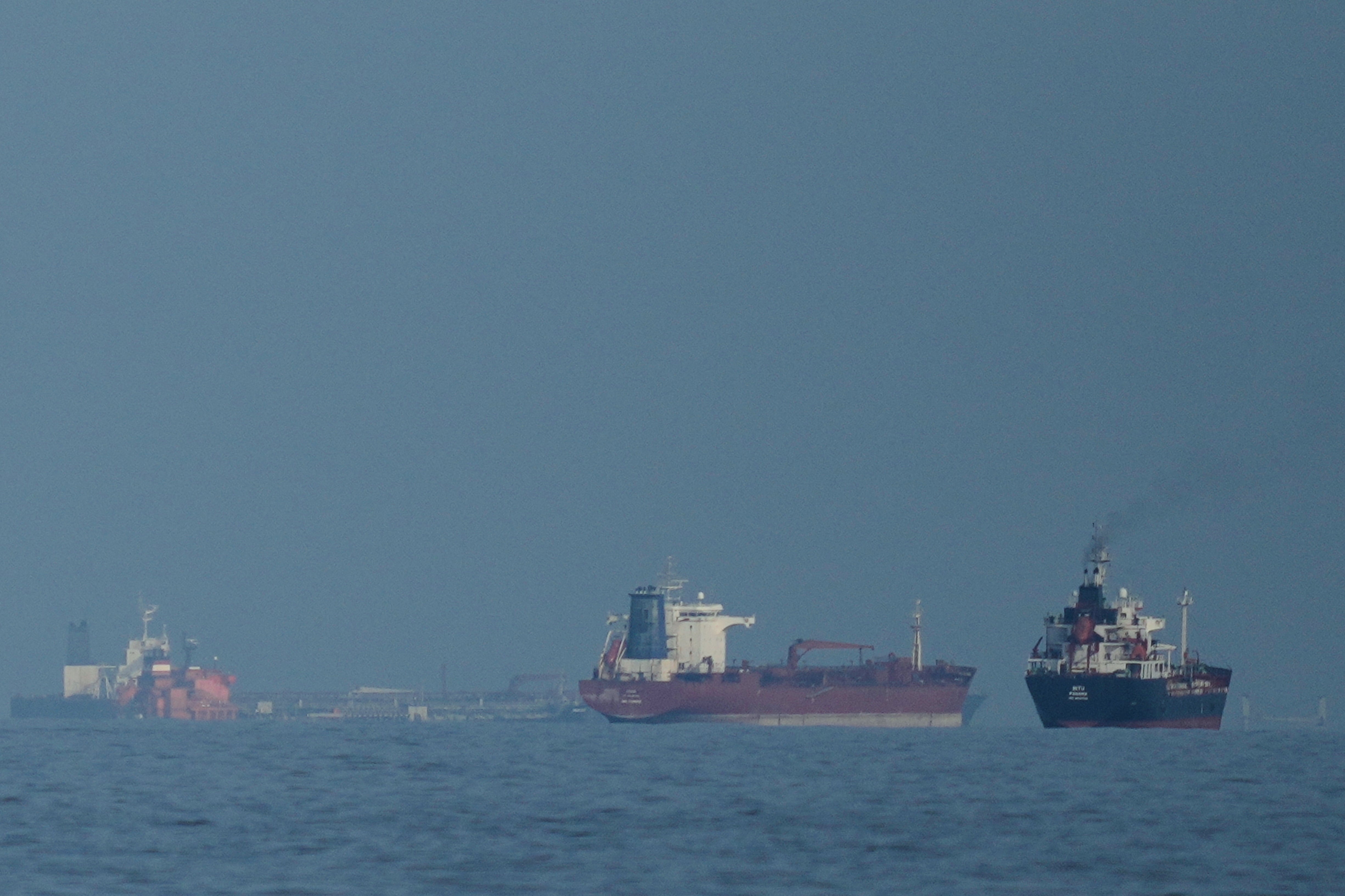 Oil tankers and cargo ships line up in the Strait of Hormuz as seen from Khor Fakkan in the United Arab Emirates (Altaf Qadri/AP)