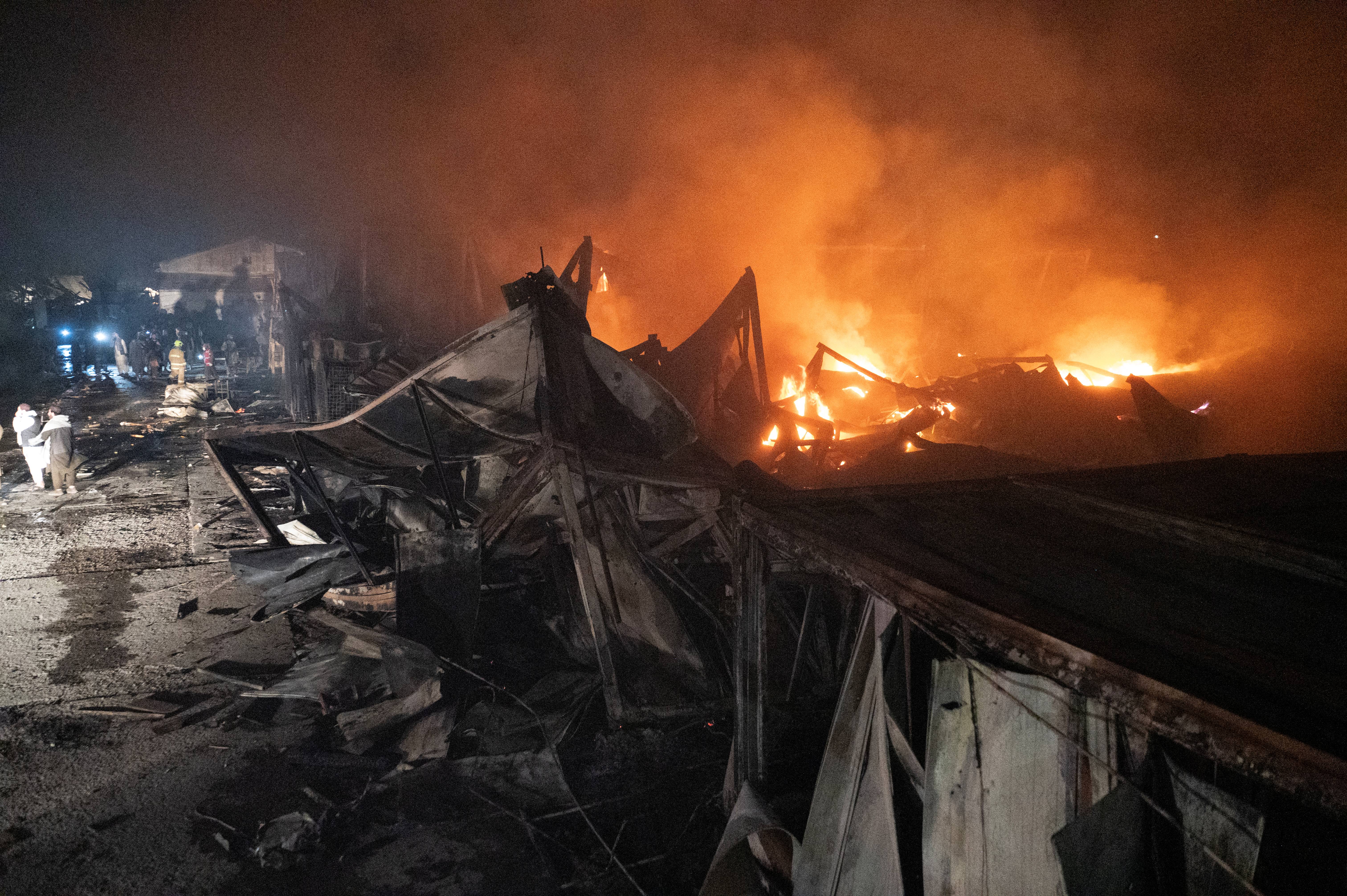Afghan firefighters and Taliban security personnel work to extinguish fires after Pakistani airstrikes allegedly hit the Secondary Rehabilitation Services Centre in Kabul on 16 March 2026
