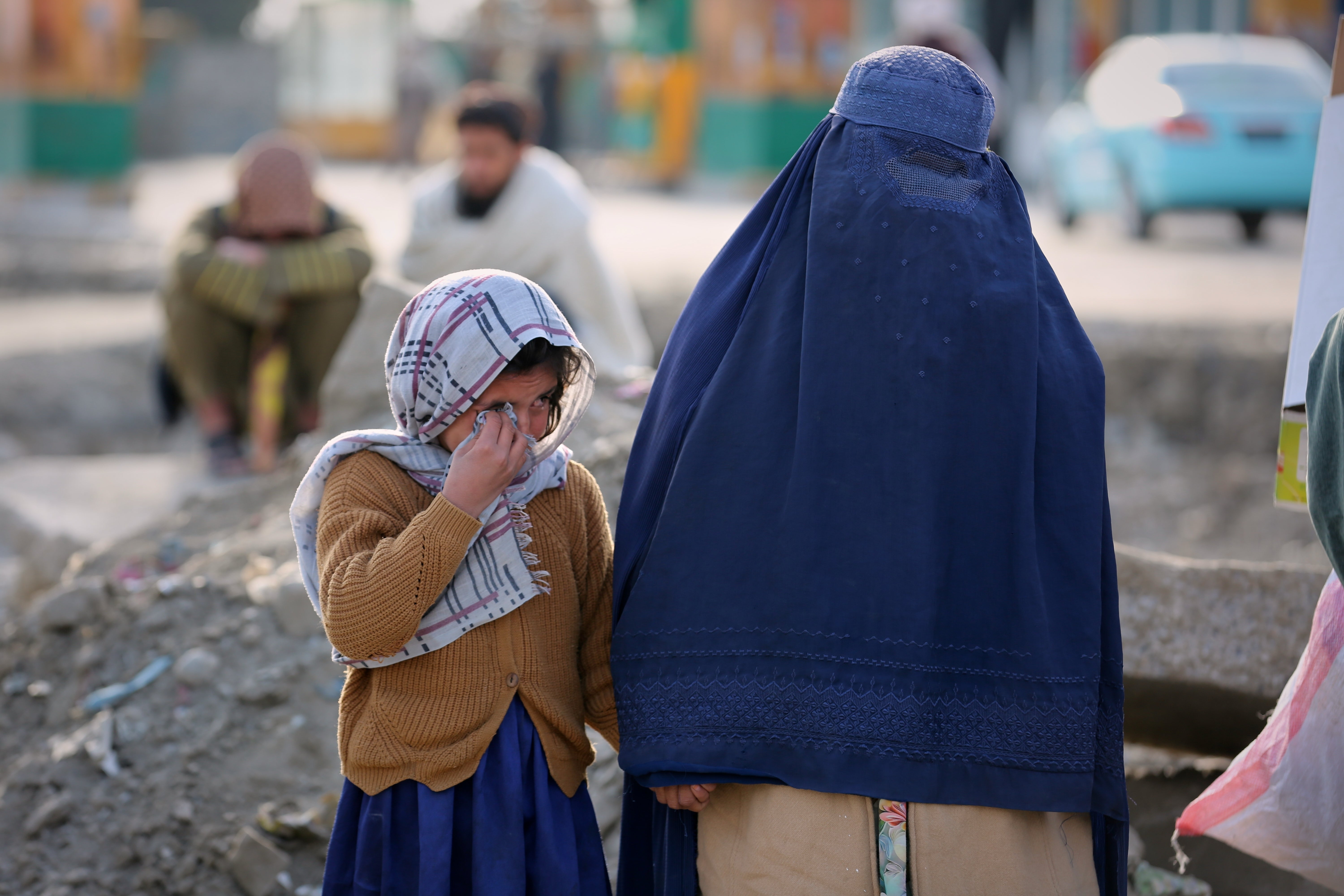 A little girl and a woman watch as rescue workers and officials inspect the site of a late-Monday airstrike at a drug rehabilitation hospital in Kabul, Afghanistan, Tuesday, March 17, 2026. (AP Photo/Siddiqullah Alizai)