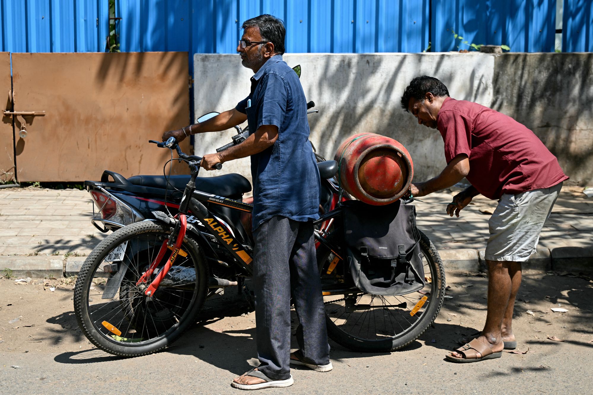 A man fastens a newly purchased LPG cylinder onto his cycle outside a gas agency in Chennai on 11 March 2026