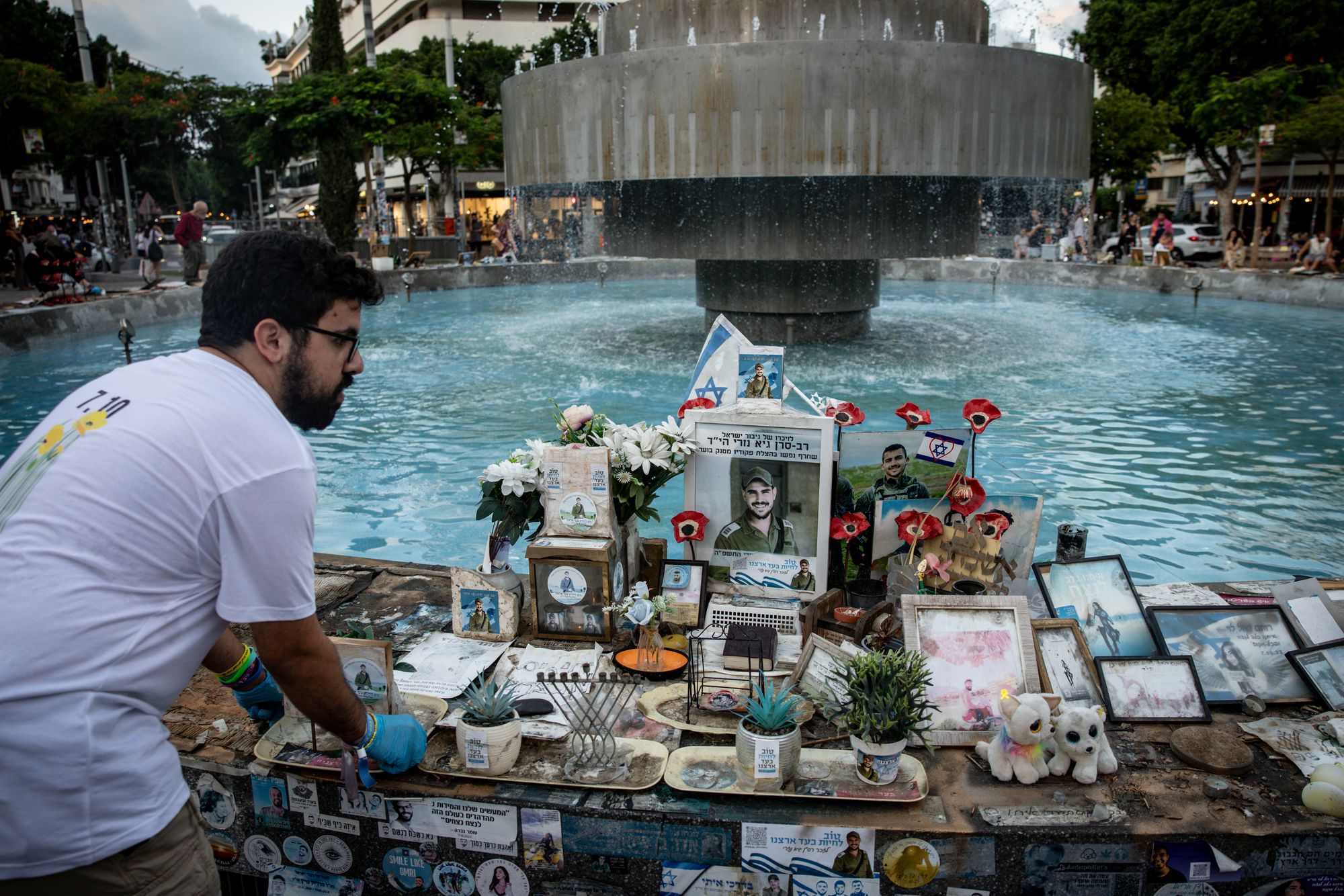 A man clears photos and belongings of the October 7, 2023 victims at a memorial in Tel Aviv