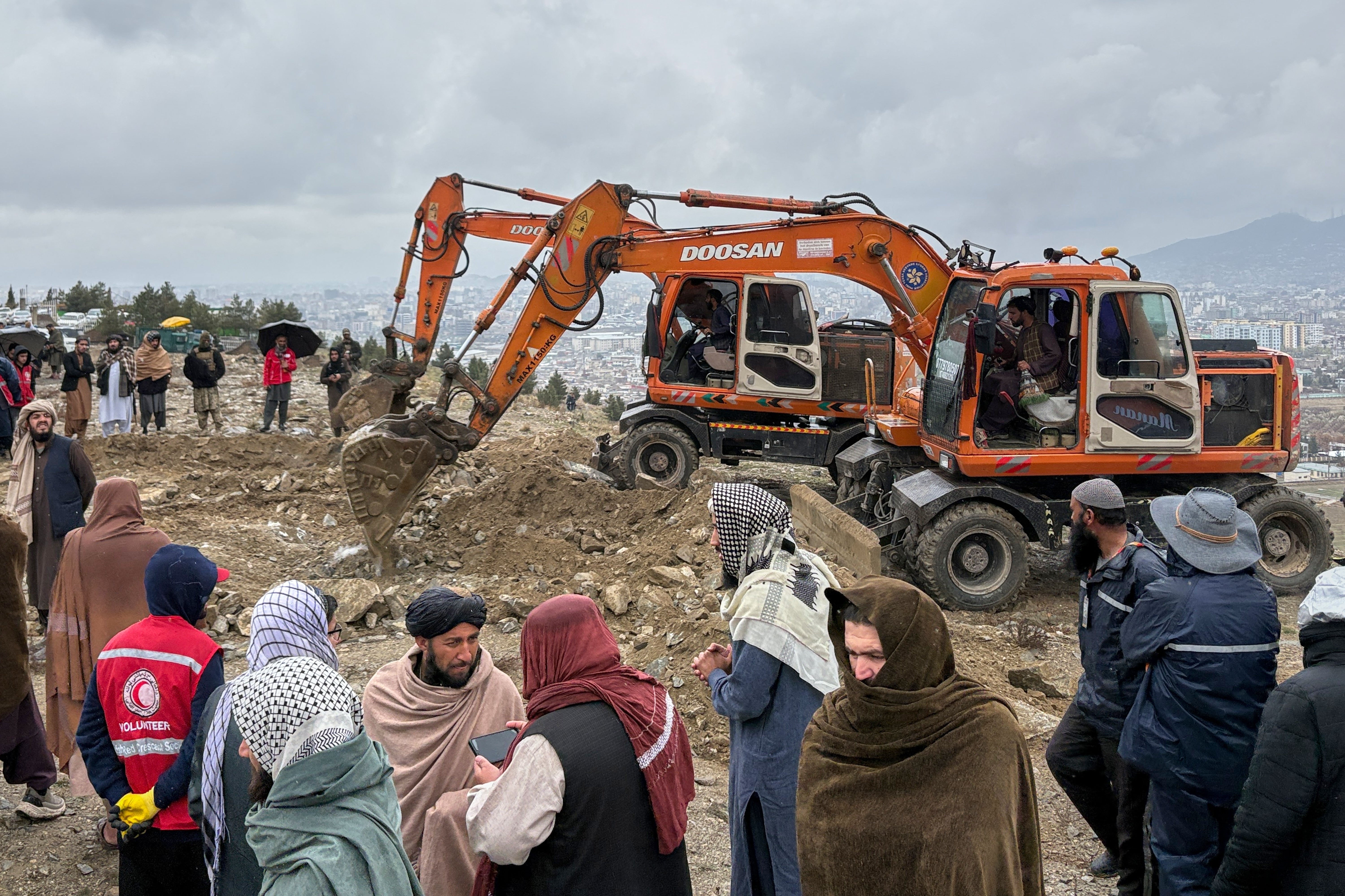 Bulldozers dig graves for victims of an airstrike on a drug rehabilitation hospital in Kabul