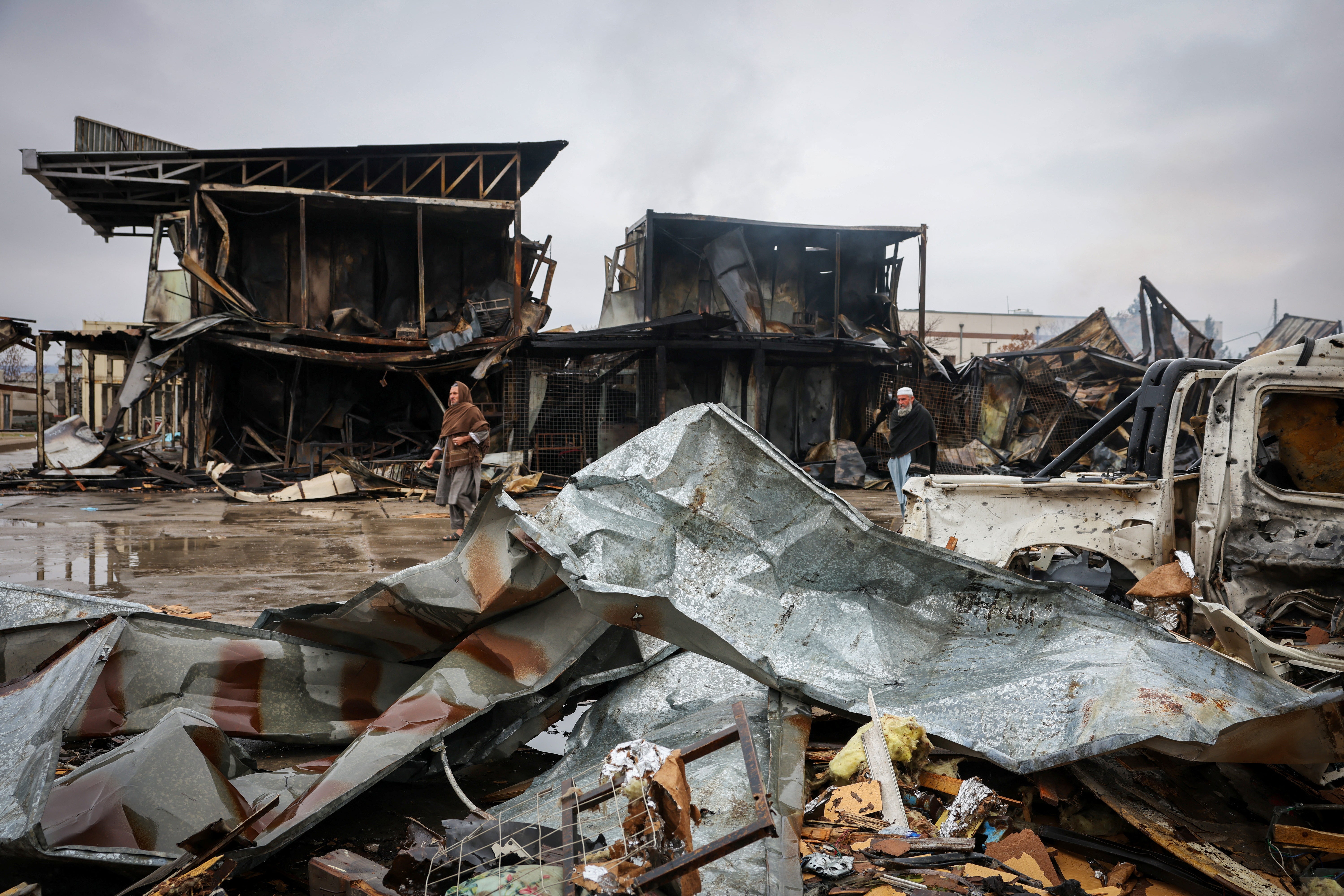 Afghan men walk next to a drug rehabilitation hospital destroyed in an alleged Pakistani airstrike in Kabul