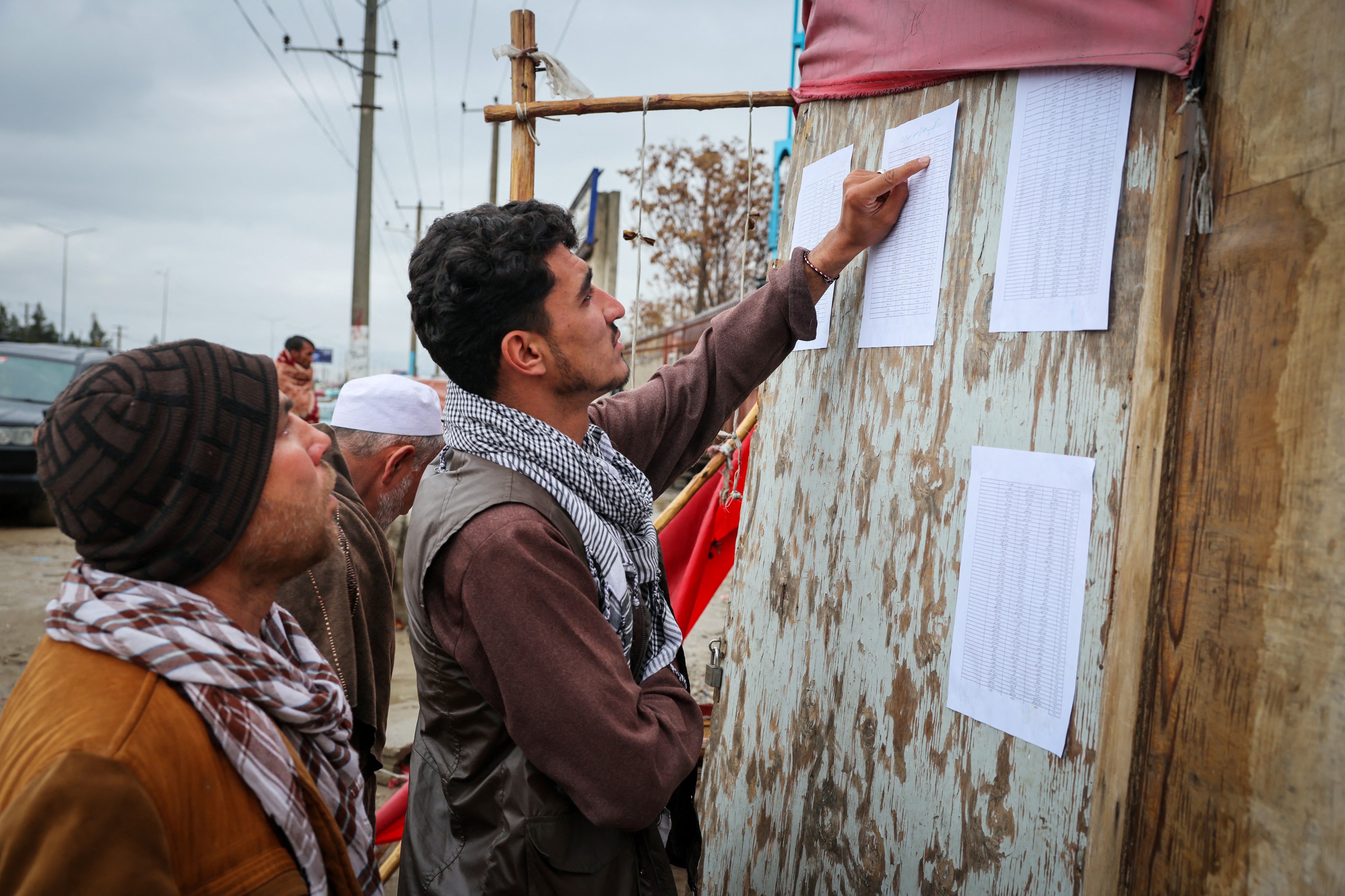 People search for the names of their missing relatives on a list at the site of a drug rehabilitation hospital that was destroyed in what the Taliban said was a Pakistani strike in Kabul