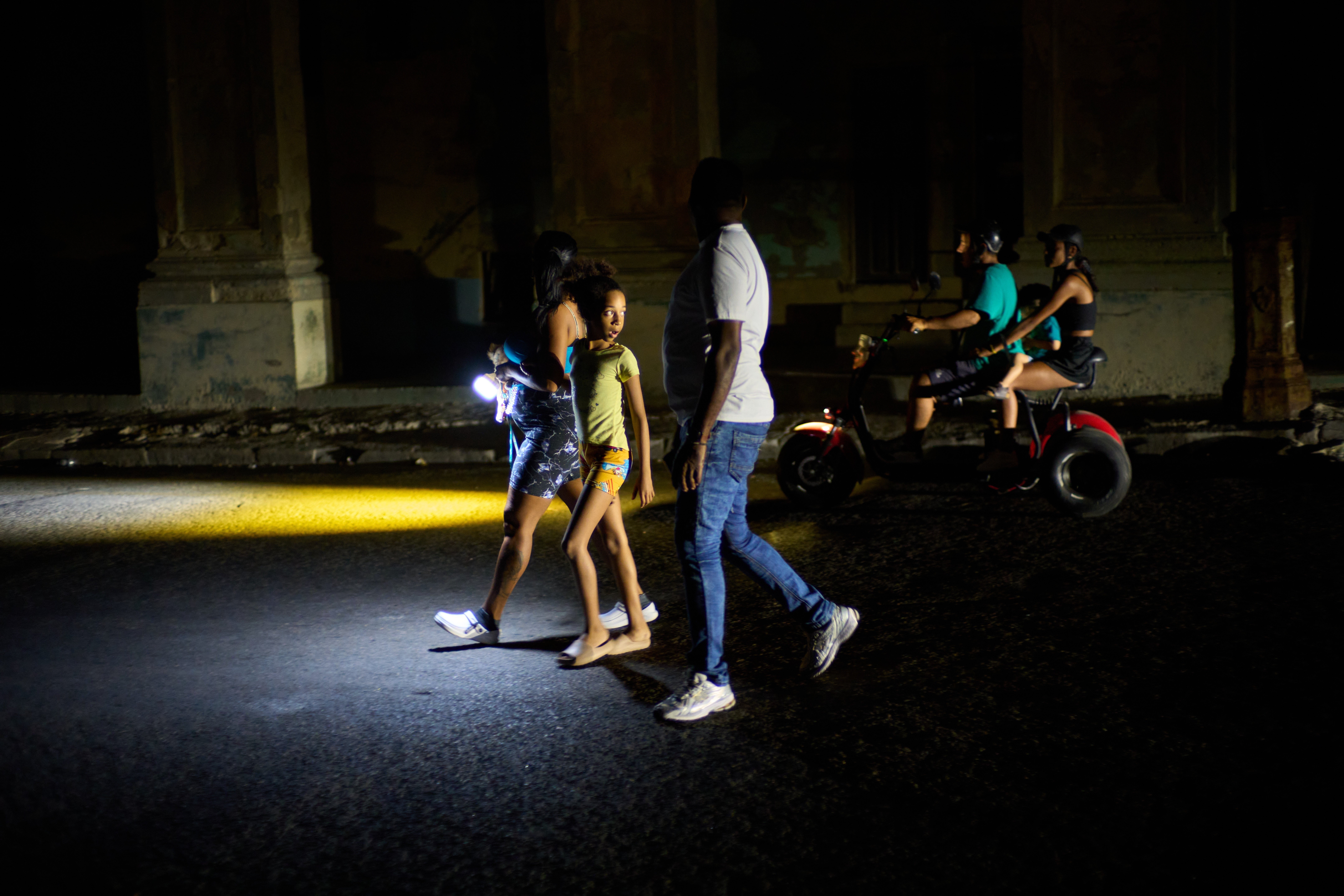 People walk on a street during a blackout in Havana