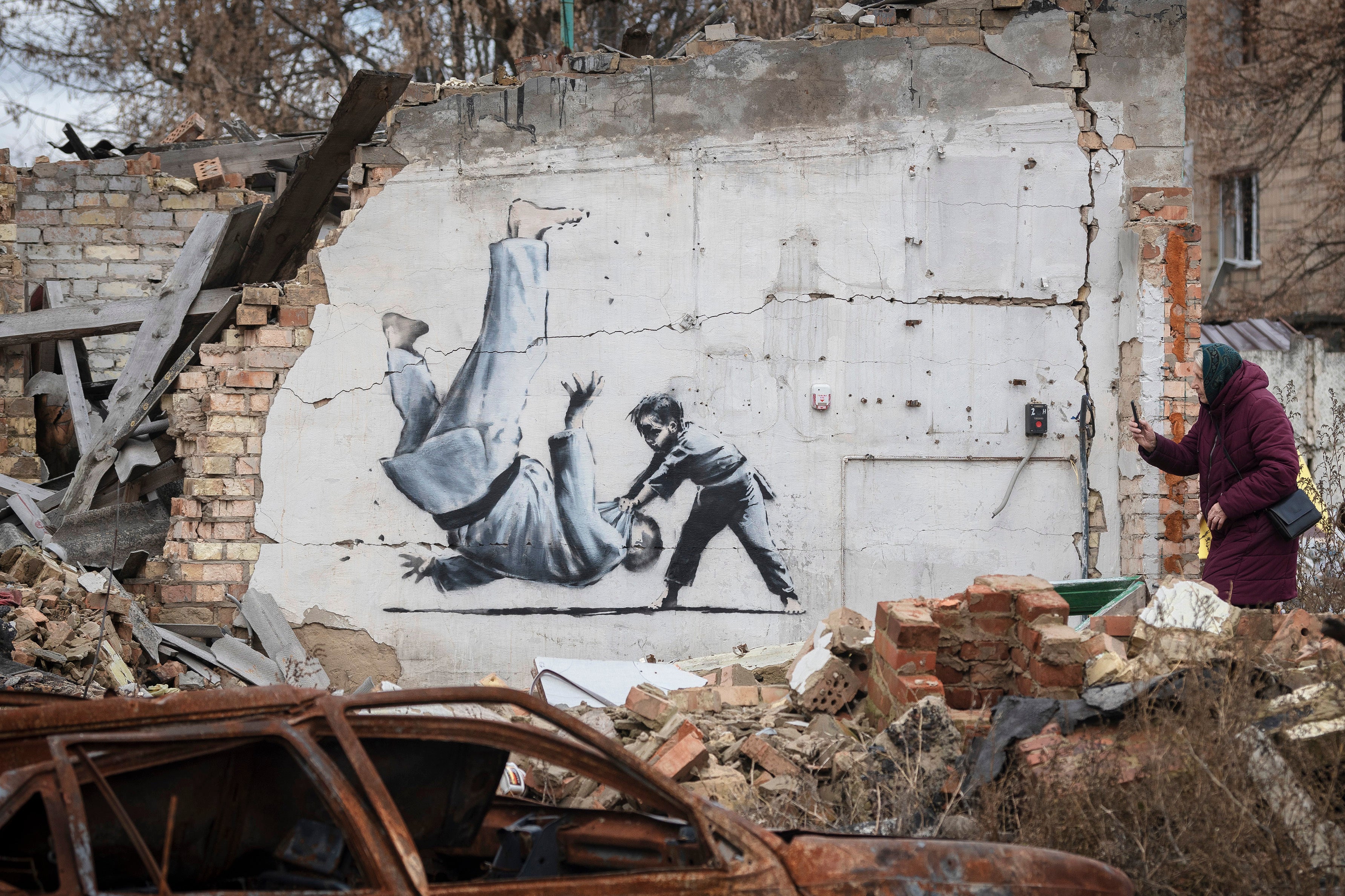 A woman takes a picture of artwork that might have been made by Banksy in Borodyanka, Kyiv region, Ukraine