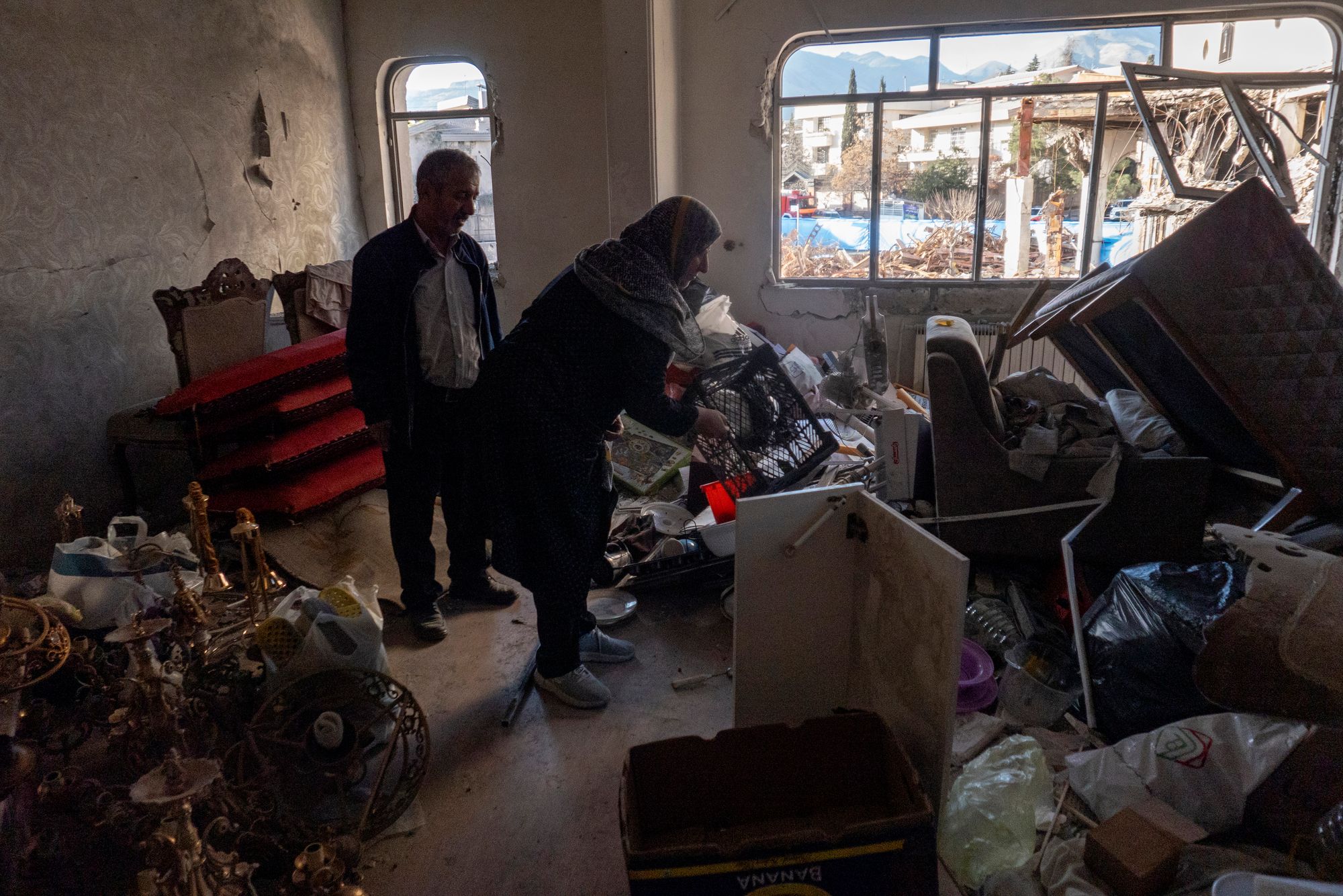 Two people sift through debris inside a residential and commercial building on March 21 in the Shahrak-e Gharb neighborhood of Tehran