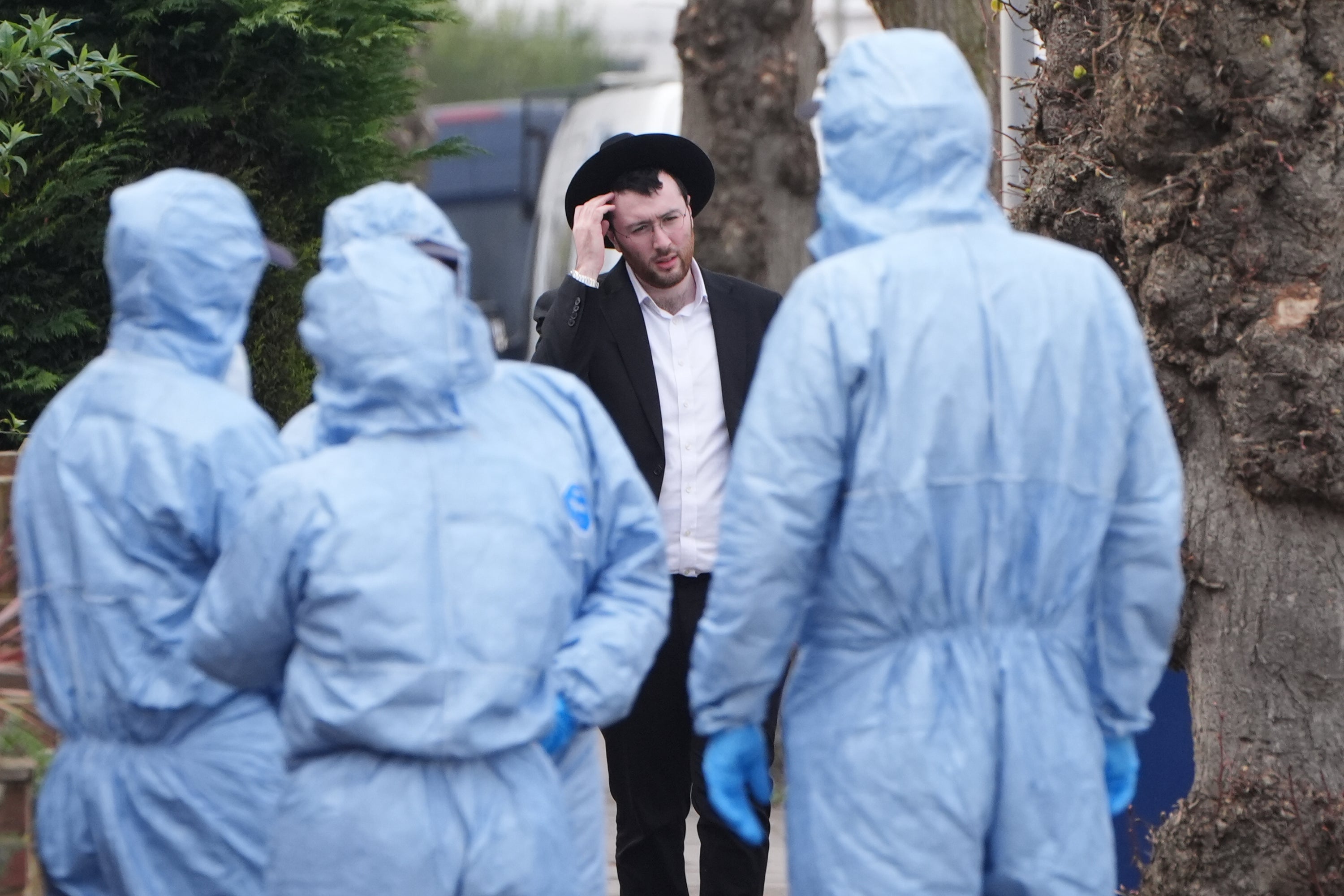 Police officers search on Brookside Road at the junction with Russell Gardens near to the scene in Highfield Road, Golders Green, London