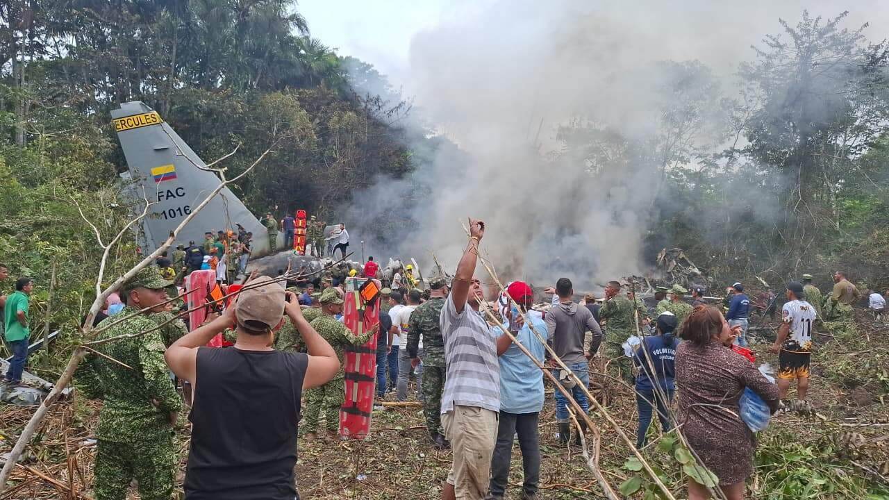 People stand around a military cargo plane that crashed after taking off from Puerto Leguizamo, Colombia, a remote municipality in the Amazonian province of Putumayo, Monday, 23 March 2026