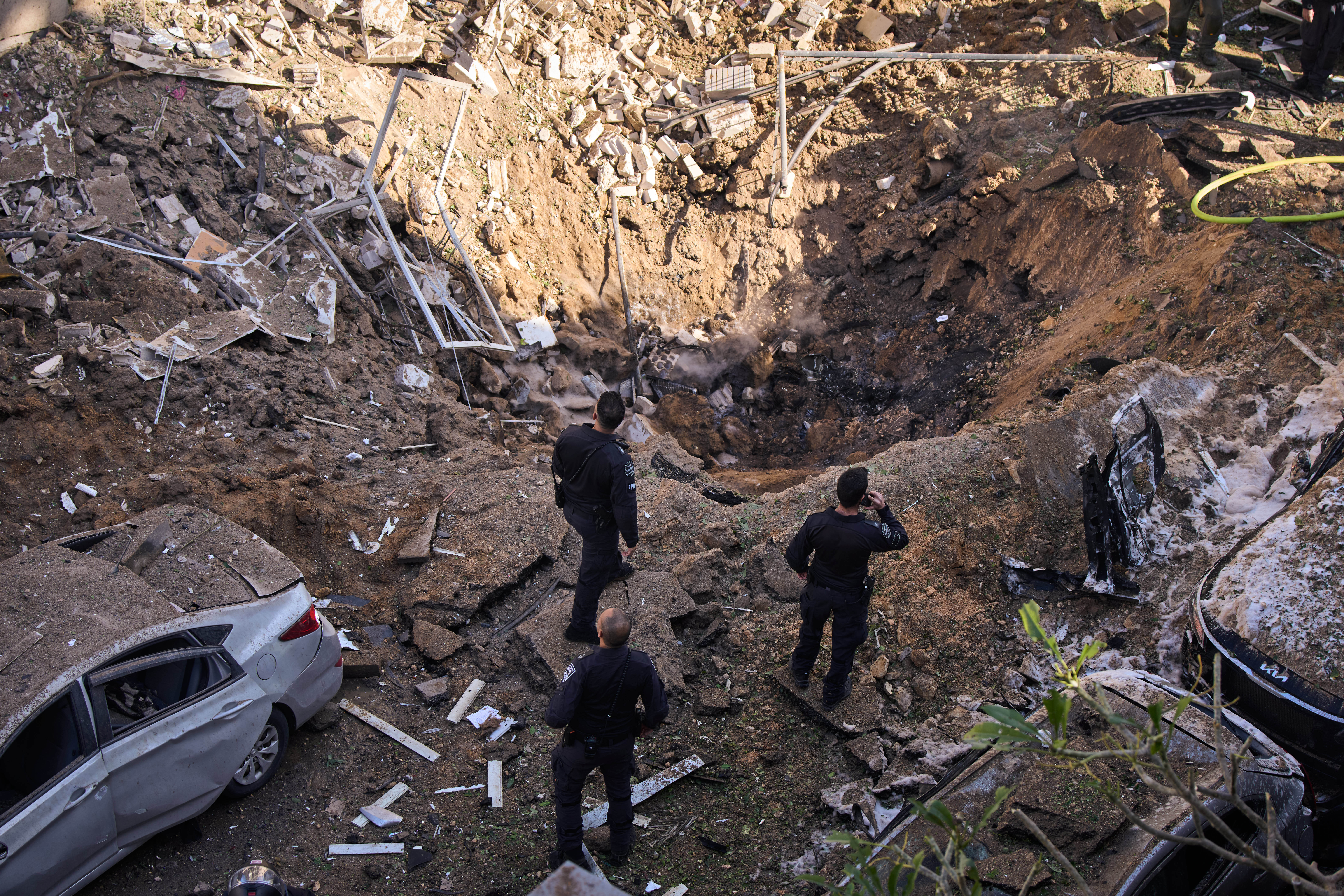 Israeli security forces and rescue teams inspect the site of an Iranian missile strike in Tel Aviv, on Tuesday