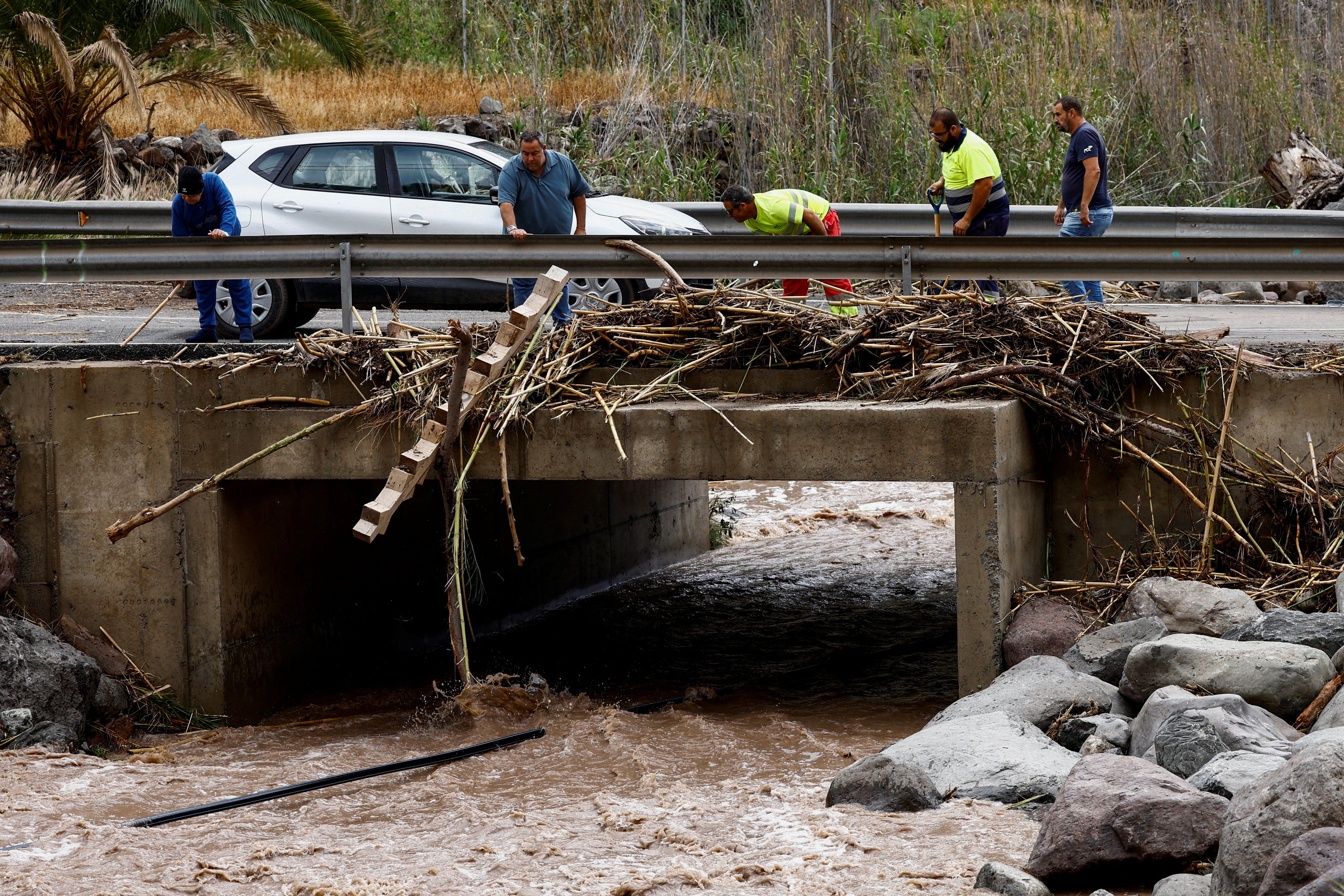 People clean a road in Cercados de Espino on the island of Gran Canaria after heavy rains