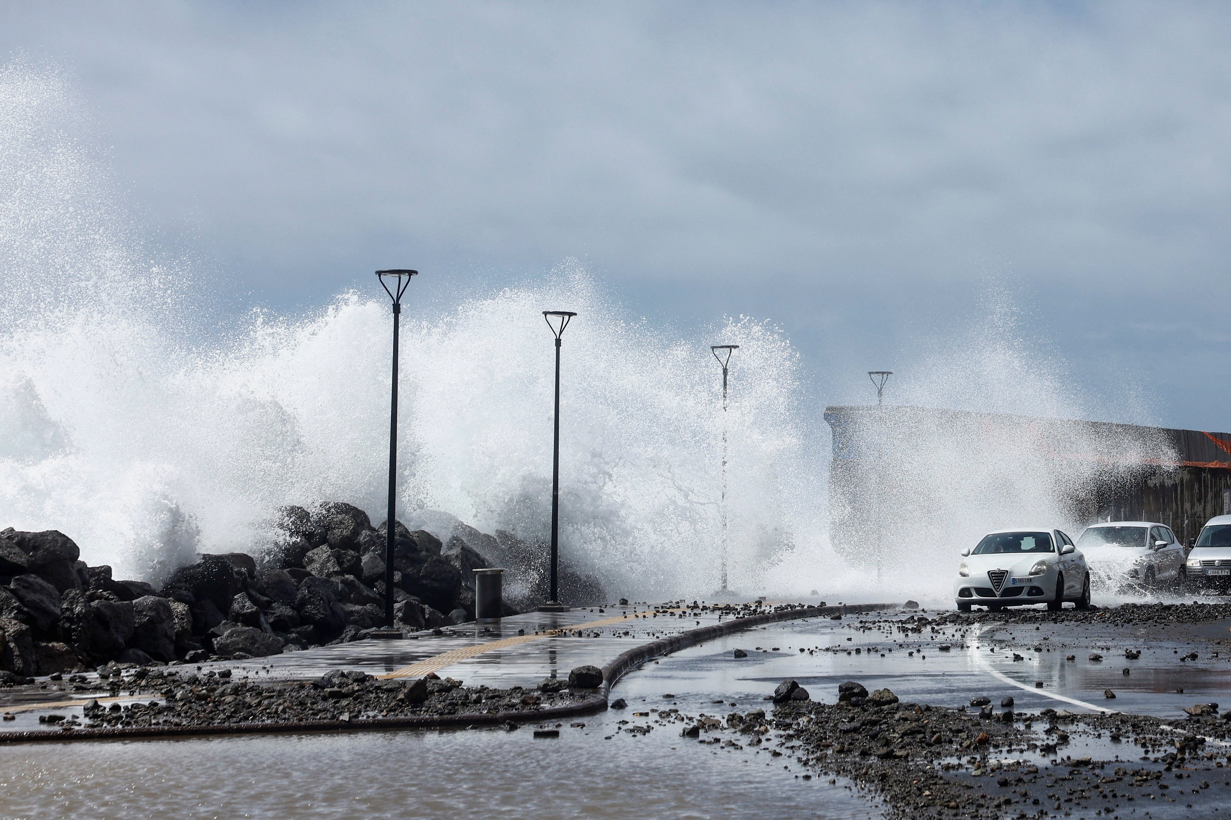 Strong waves crash onto a road next to vehicles at the port of Arguineguin on the island of Gran Canaria during an alert in the Canary Islands due to Storm Therese