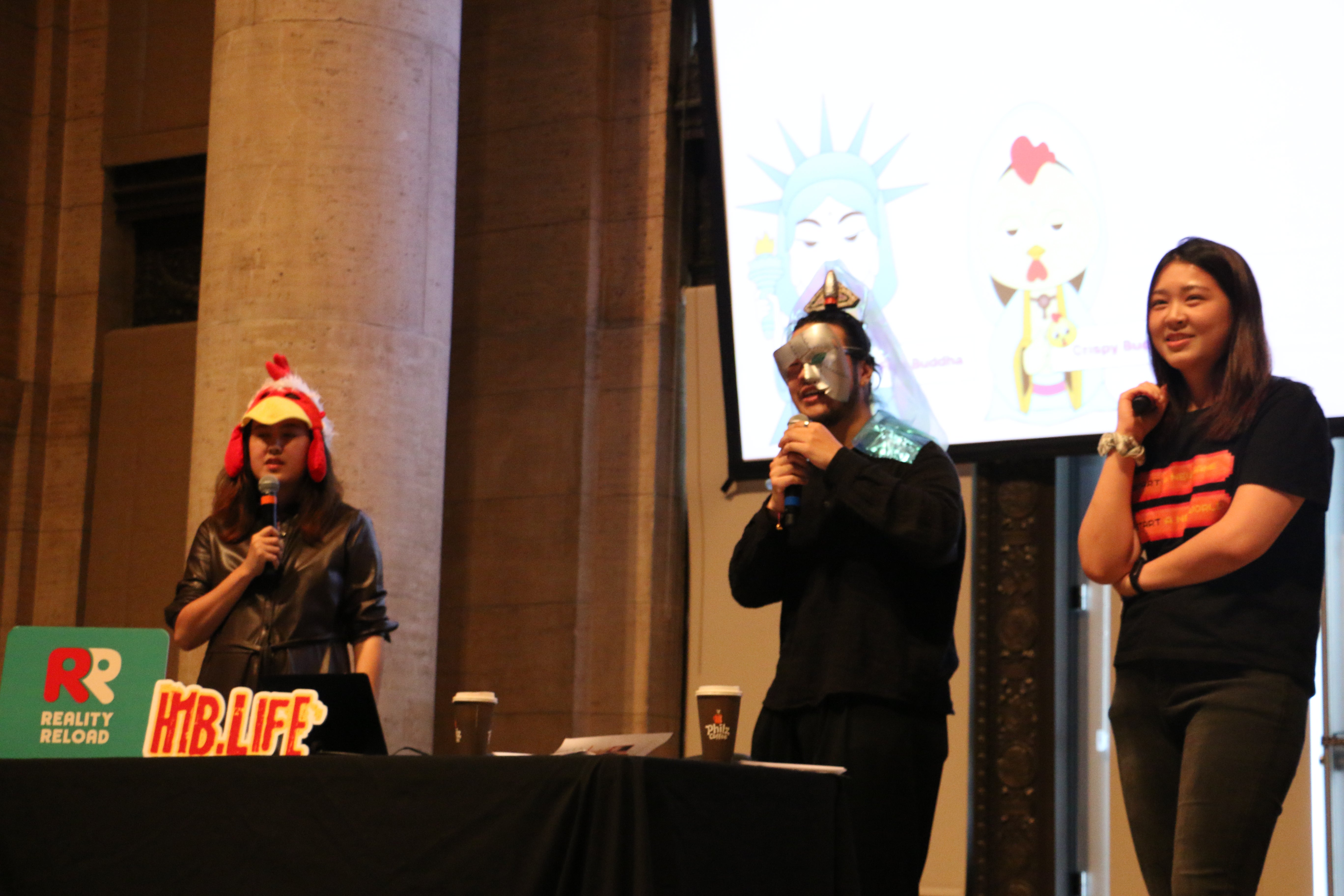 Members of Reality Reload present a GDC talk dressed as some of the game's bizarre 'Buddhas' — immigration-themed deities who will alter the player's path