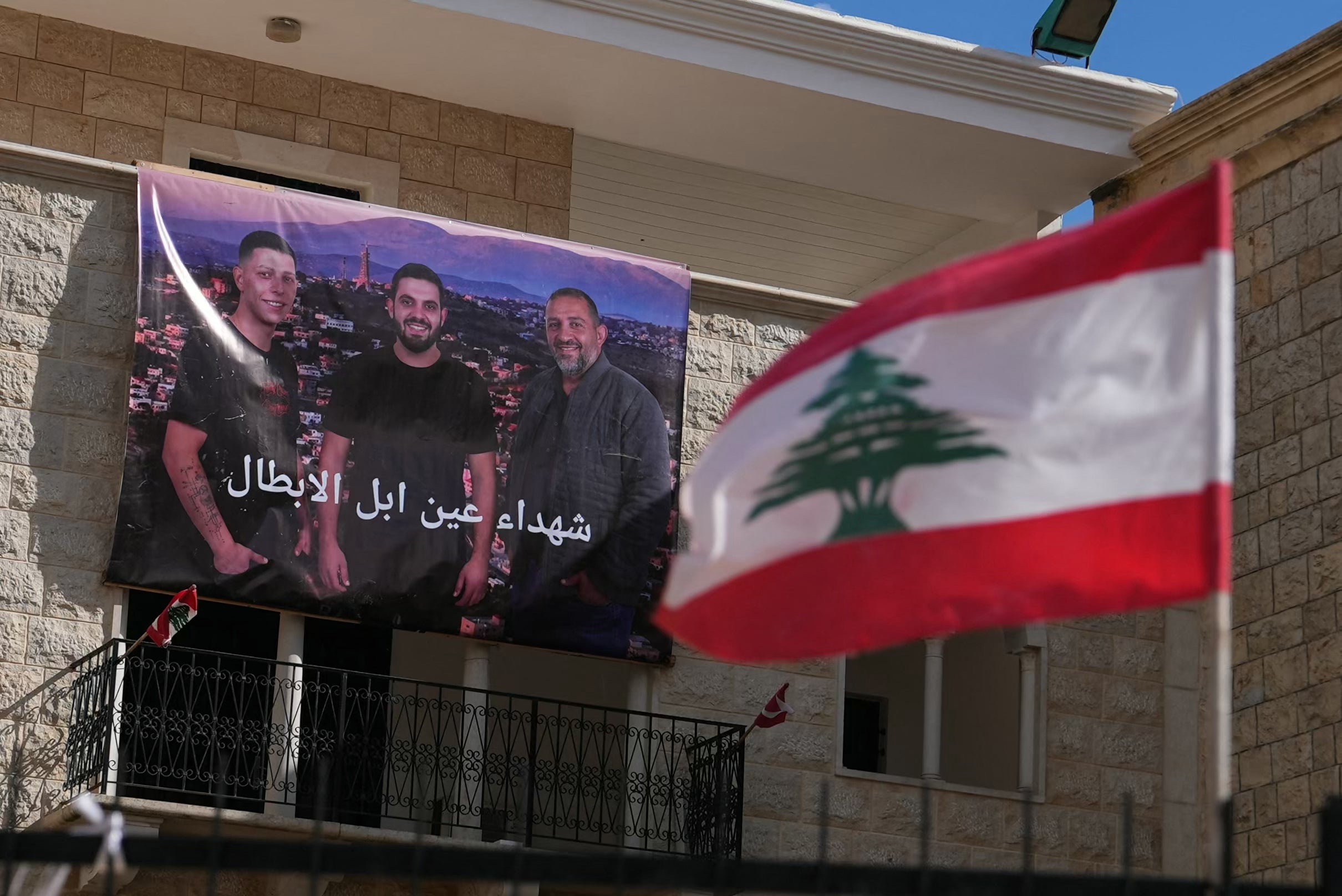 A banner that depicts the portraits of three men killed by an Israeli airstrike hangs on the wall of a building in the southern Lebanese Christian border village of Ain Ebel