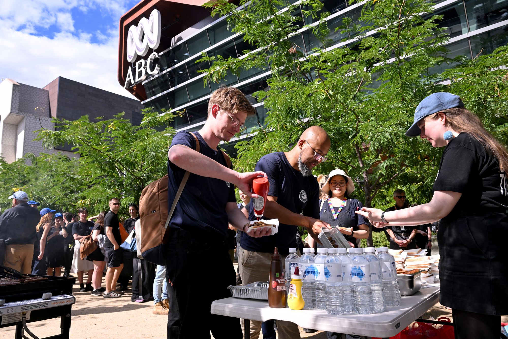 Journalists and staff line up for a sausage sizzle outside the Australian Broadcasting Corporation (ABC) headquarters during a strike demanding better pay and protections to stop artificial intelligence taking their jobs, in Melbourne