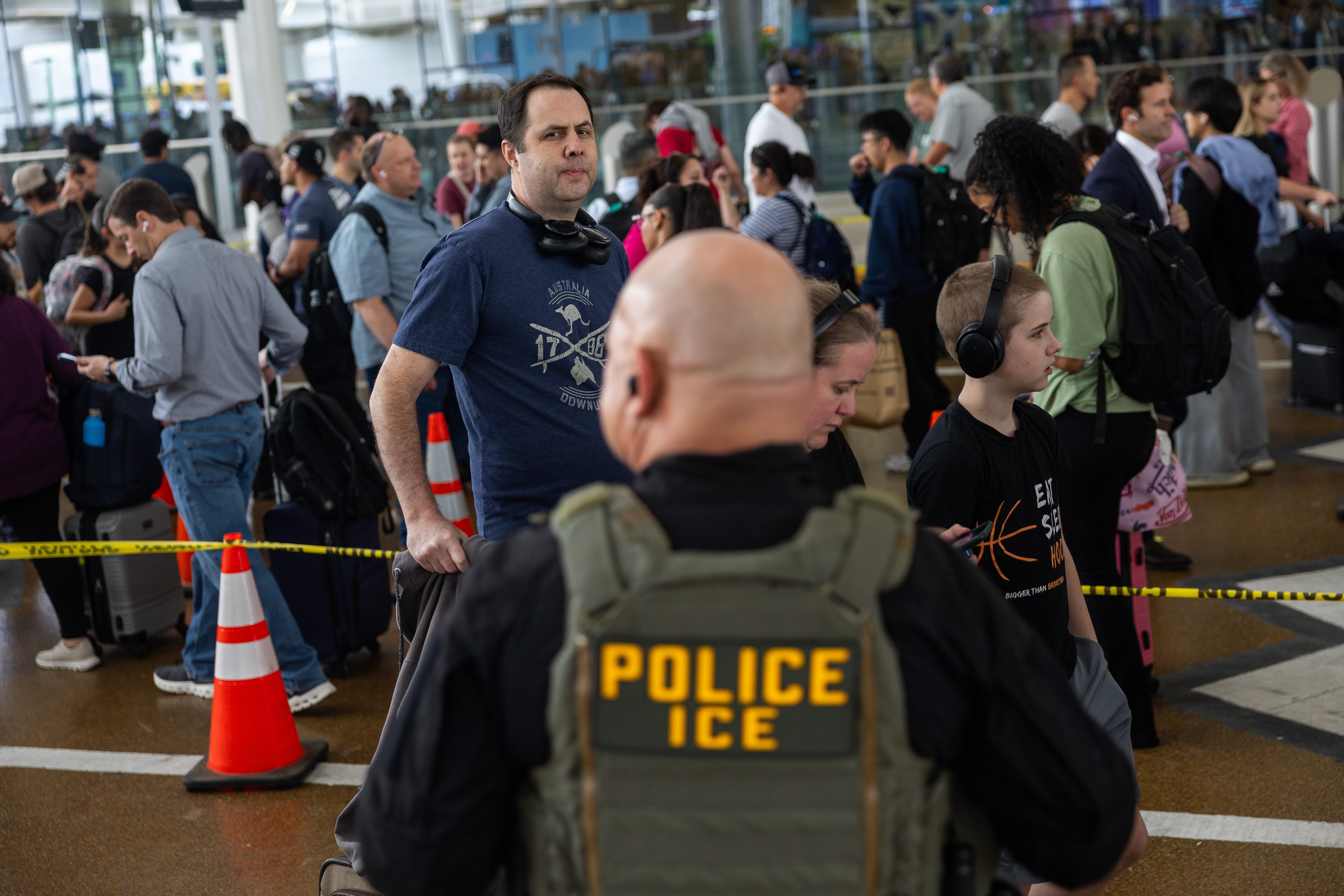 Would-be travelers wait in line at Houston's George Bush Intercontinental Airport as an ICE agent looks on, on 24 March 2026, amid a partial government shutdown causing similar scenes around the country