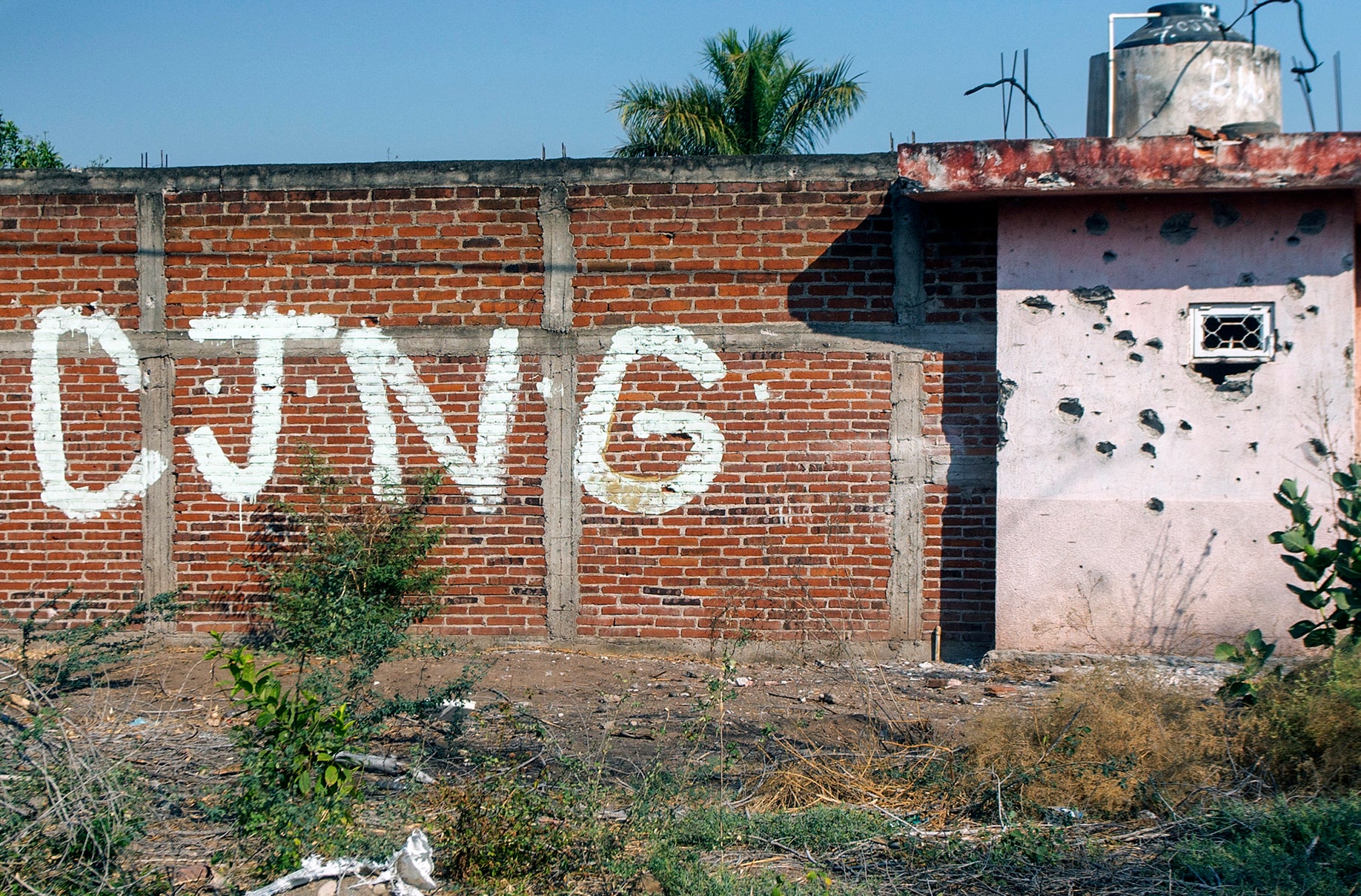 A bullet-riddled wall bearing the initials of the criminal group Cartel Jalisco Nueva Generacion at the entrance of the community of Aguililla, state of Michoacan, Mexico, on April 23, 2021