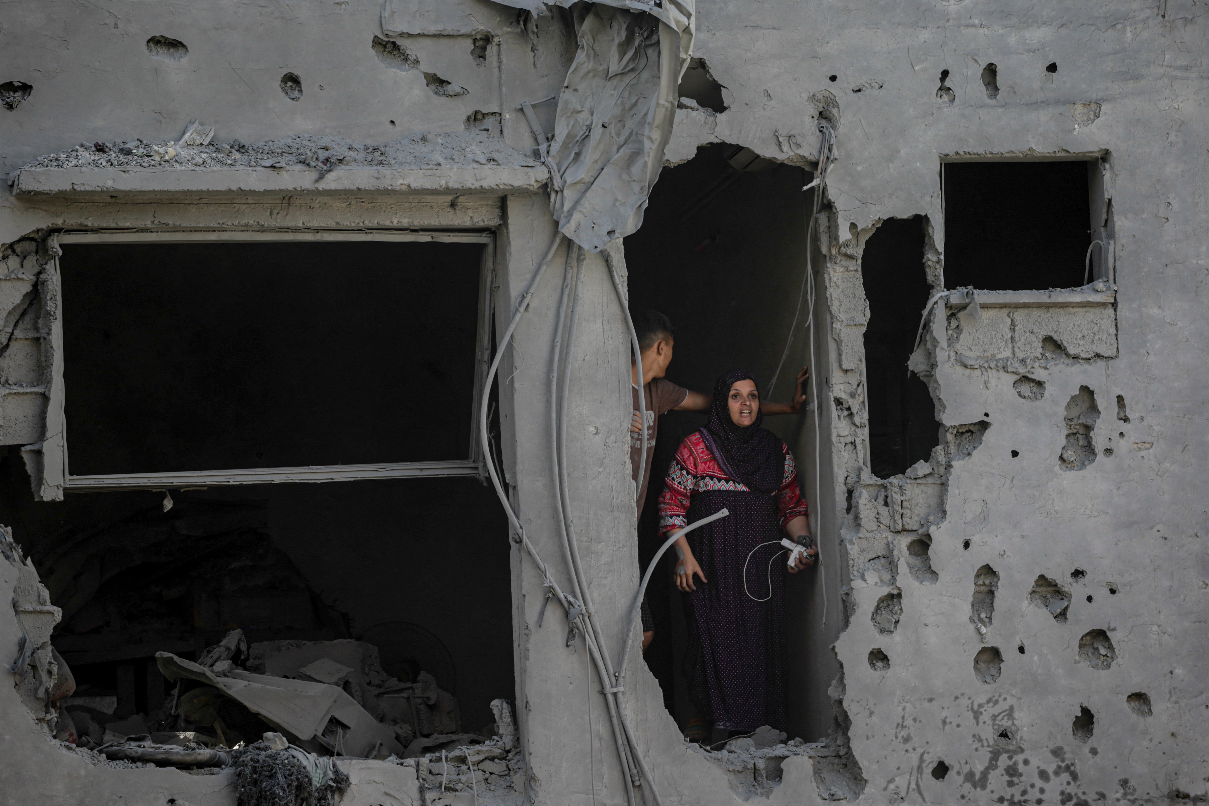 A Palestinian woman stands in a heavily damaged building in Al-Shatea refugee camp in Gaza City