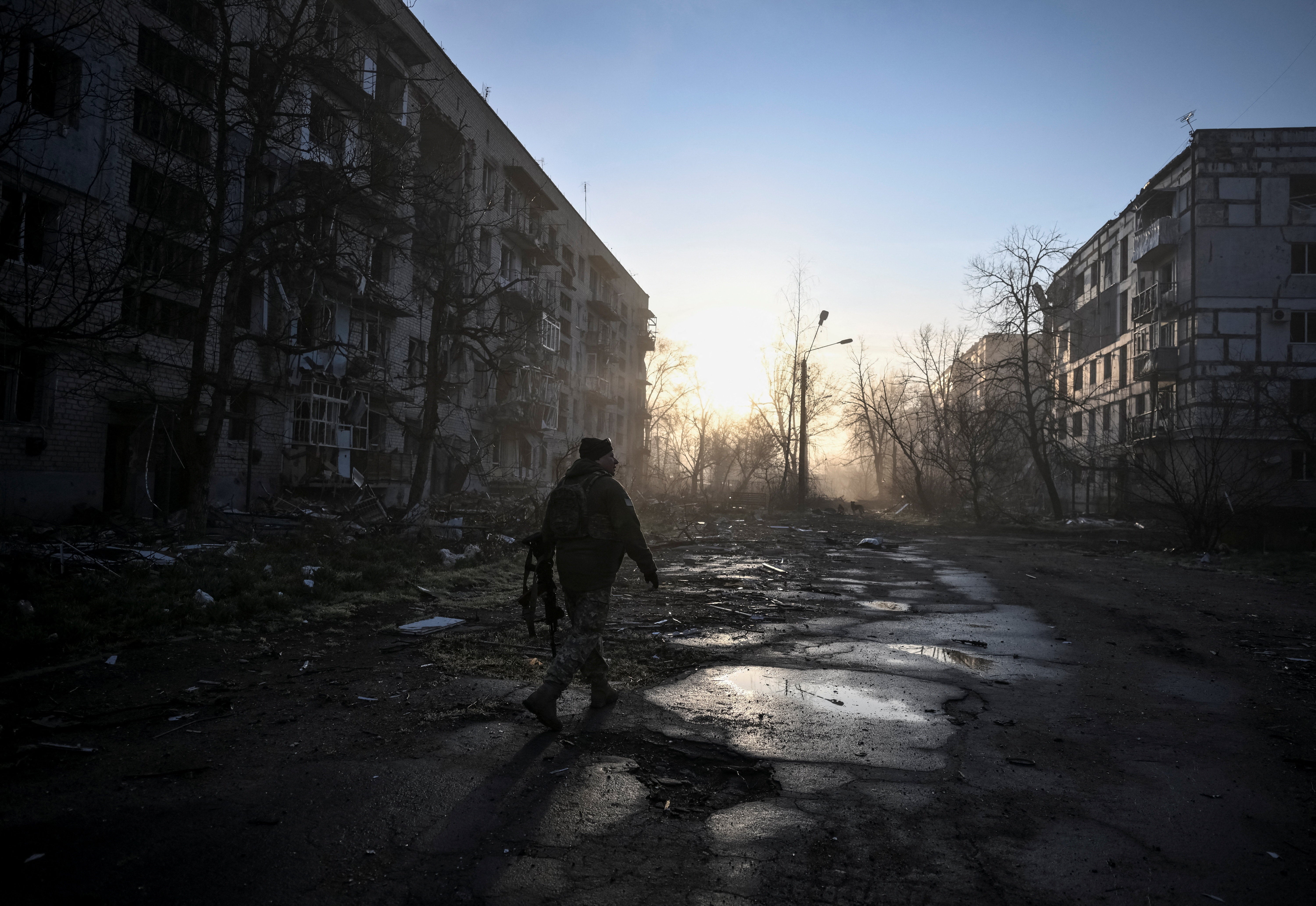 A Ukrainian service member walks near residential buildings damaged by Russian military strikes in the frontline town Orikhiv in Zaporizhzhia region