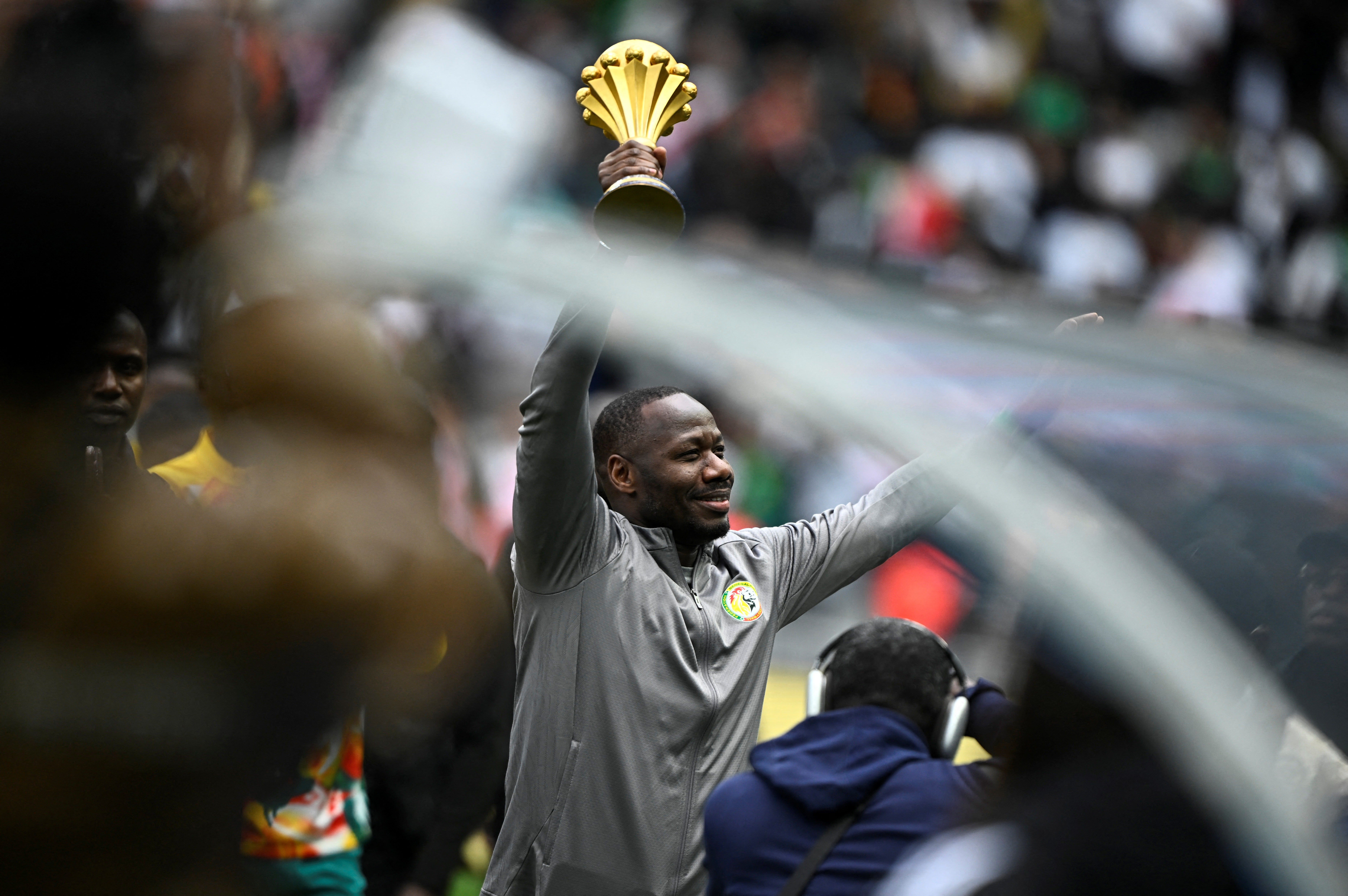 Senegal's head Coach Pape Thiaw holds the African Cup of Nations trophy aloft at the Stade de France
