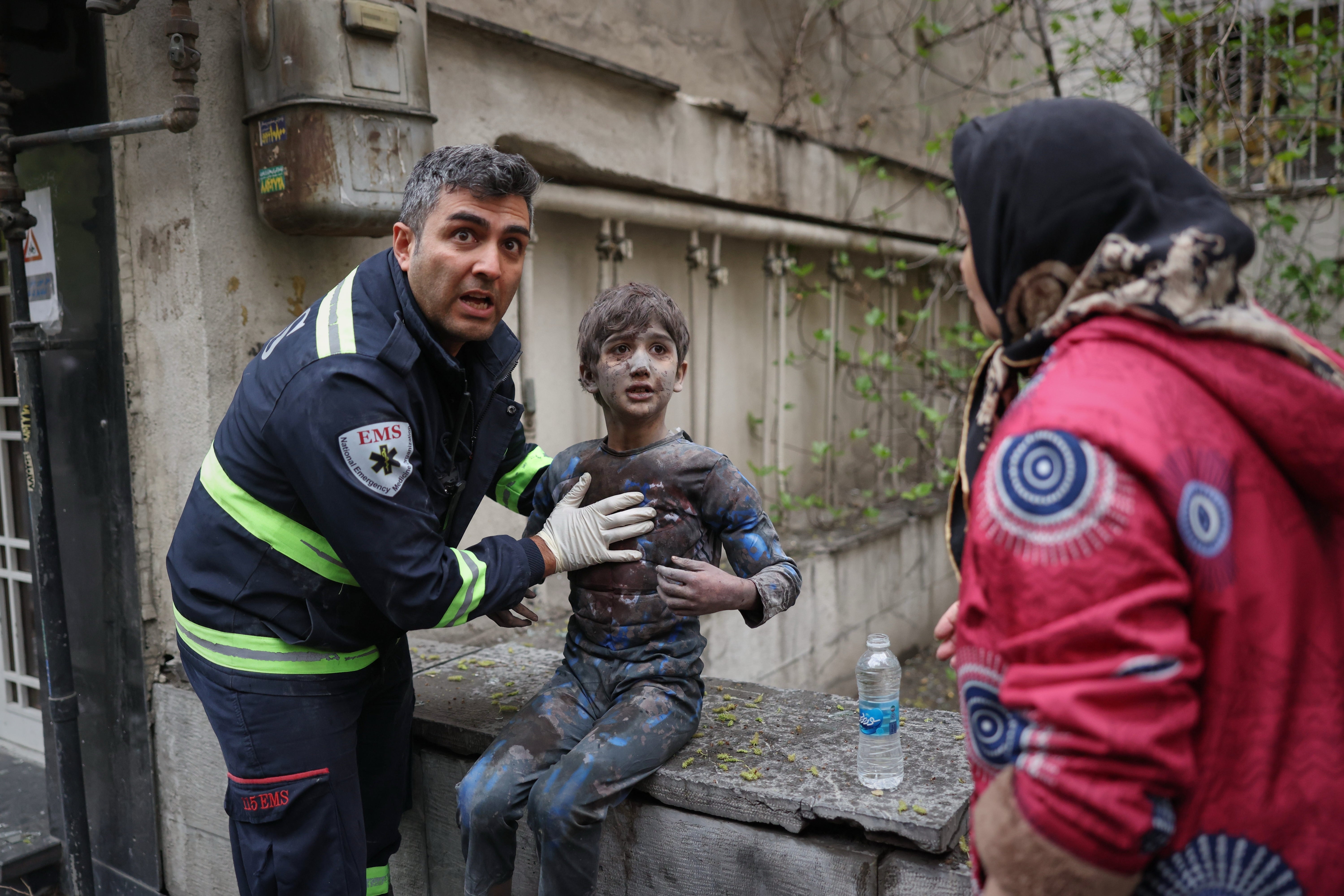 A first responder assists an injured boy following a strike that hit a residential building amid the U.S.-Israeli military campaign in Tehran, Iran, Saturday, March 28, 2026. (AP Photo/Sajad Safari)