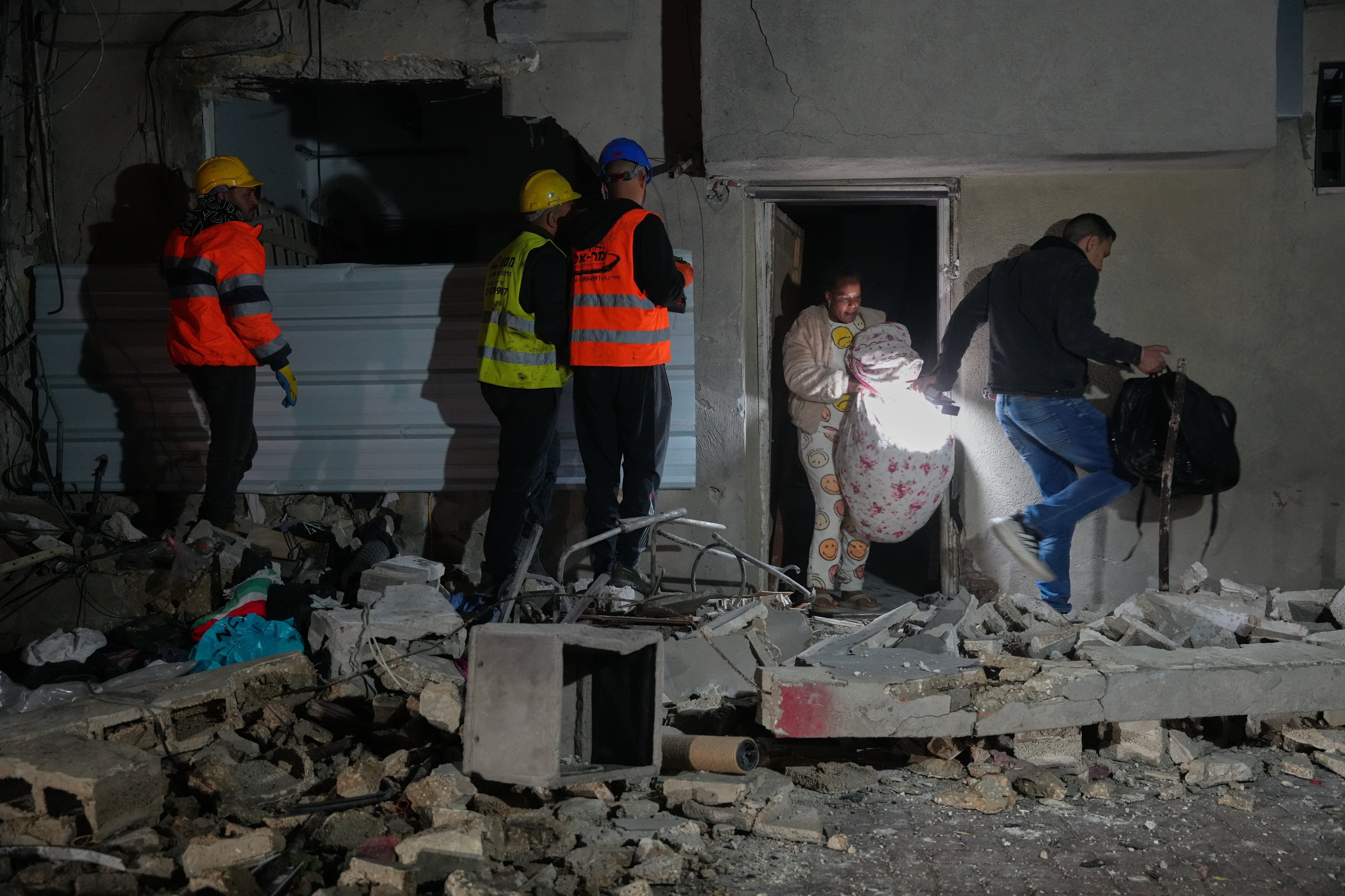 Residents carry personal belongings as they leave a building damaged in a missile strike in Tel Aviv, Israel, early Saturday, March 28, 2026. (AP Photo/Maya Levin)
