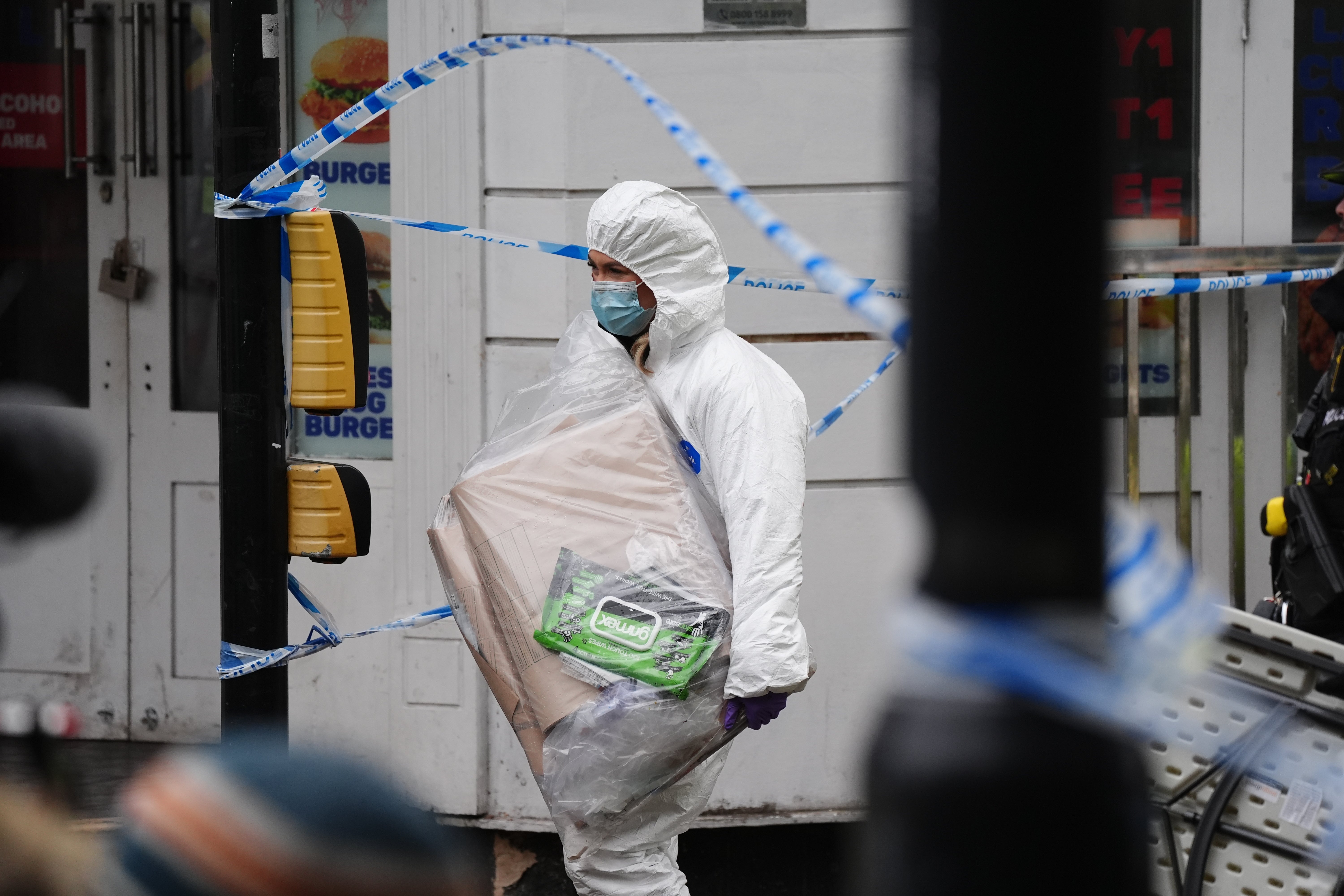 A forensic investigator carrying an evidence bag at the scene