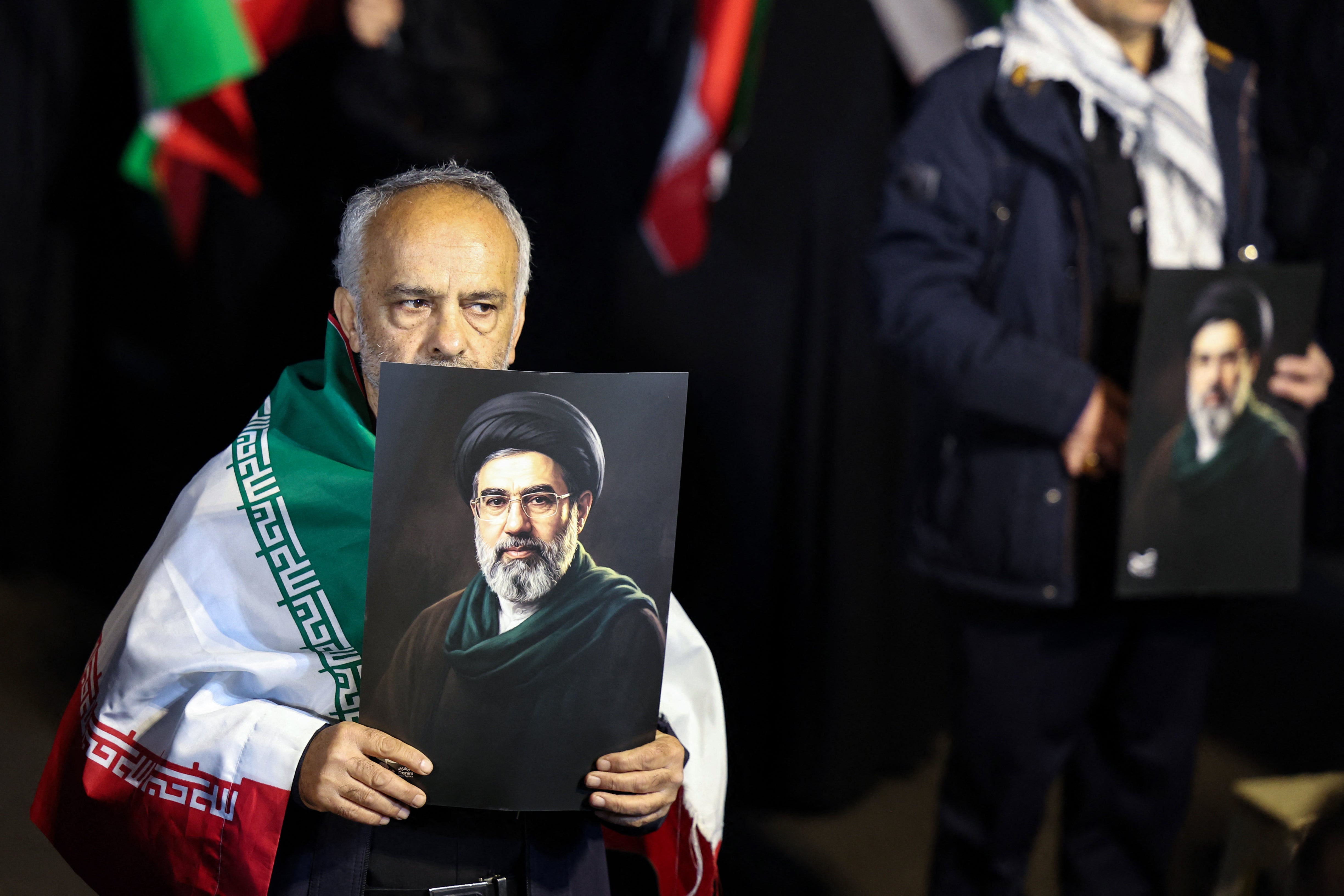 A man draped in Iran’s national flag holds a portrait of supreme leader Mojtaba Khamenei during a march in support of the armed forces in Tehran