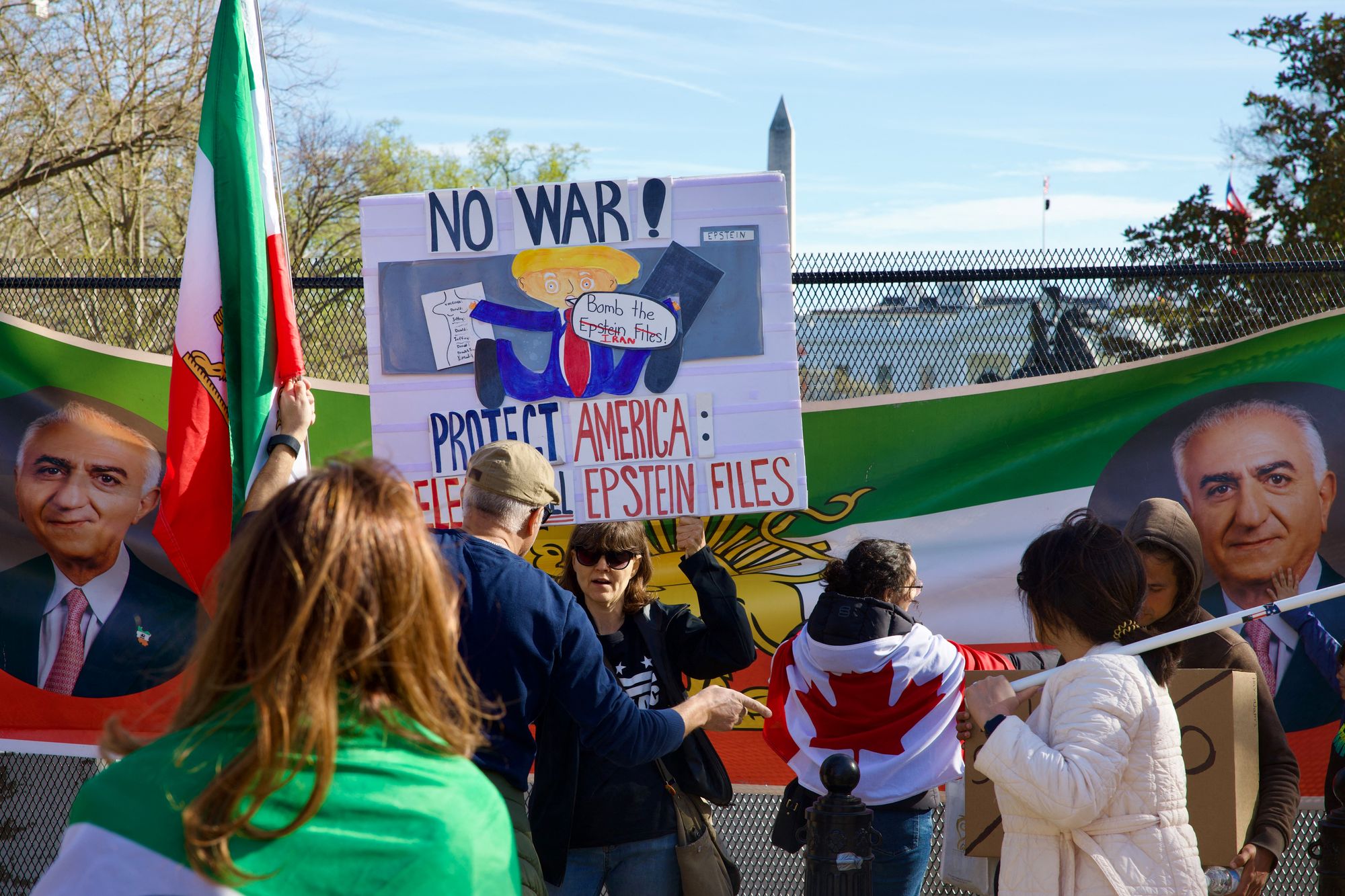 A woman holds up a sign featuring an image of Reza Pahlavi, son of the last shah of Iran, and US President Donald Trump as demonstrators march toward the White House during a rally in support of Iranians' fight for freedom, in Washington, DC, on March 29, 2026. The event, organized by DCProtests4Iran, brought together members of the Iranian diaspora from the Washington, DC metropolitan area and surrounding states. (Photo by Amid FARAHI / AFP via Getty Images)