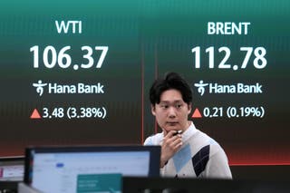 A currency trader reacts near a screen showing international oil prices at the foreign exchange dealing room of the Hana Bank headquarters in Seoul, South Korea