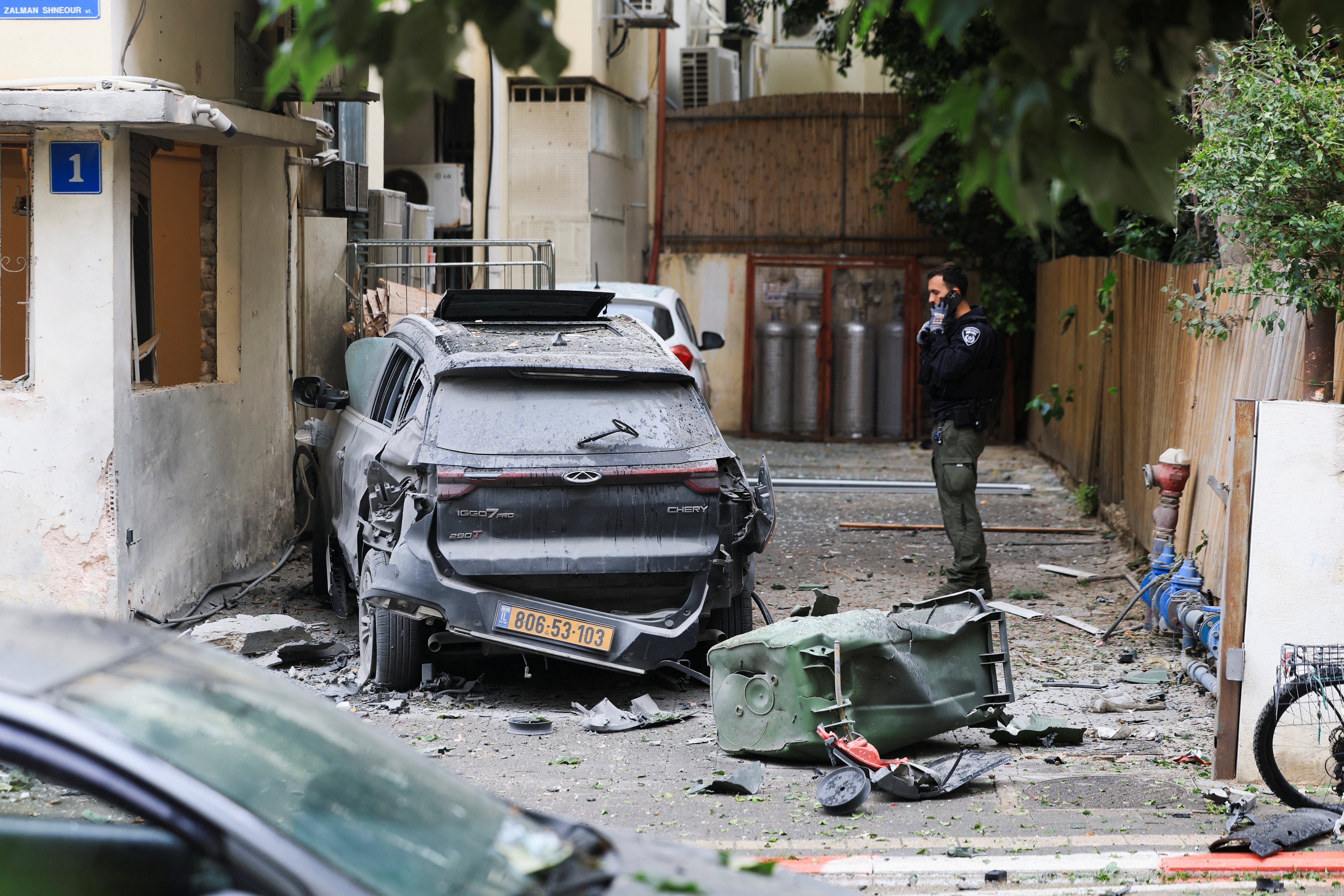 An Israeli police officer stands near a wrecked car in Tel Aviv, on 1 April