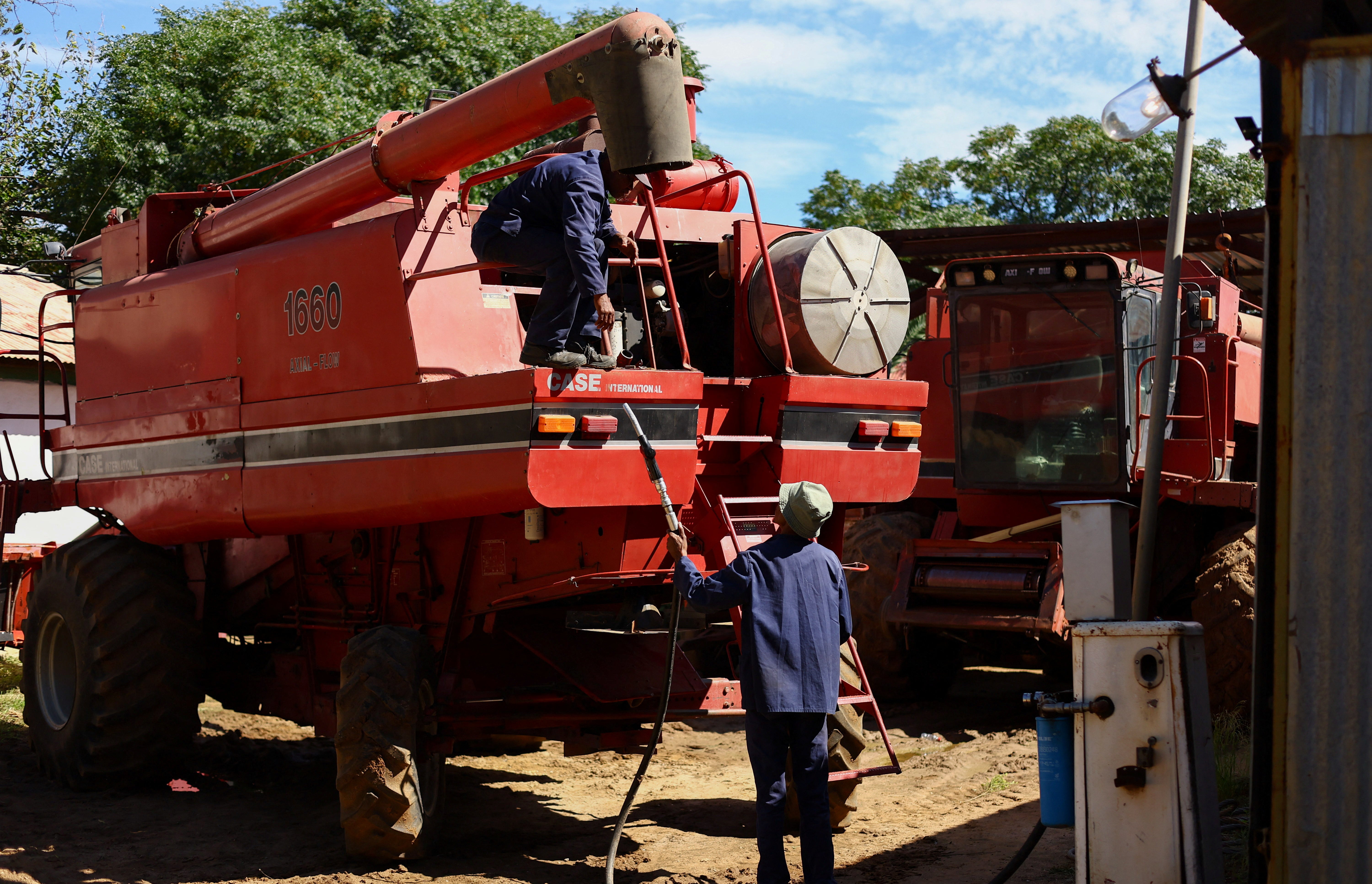Workers refuel a combine harvester from on farm fuel pump, amid concerns over securing supplies and rising fuel costs ahead of the harvest, near Lichtenburg