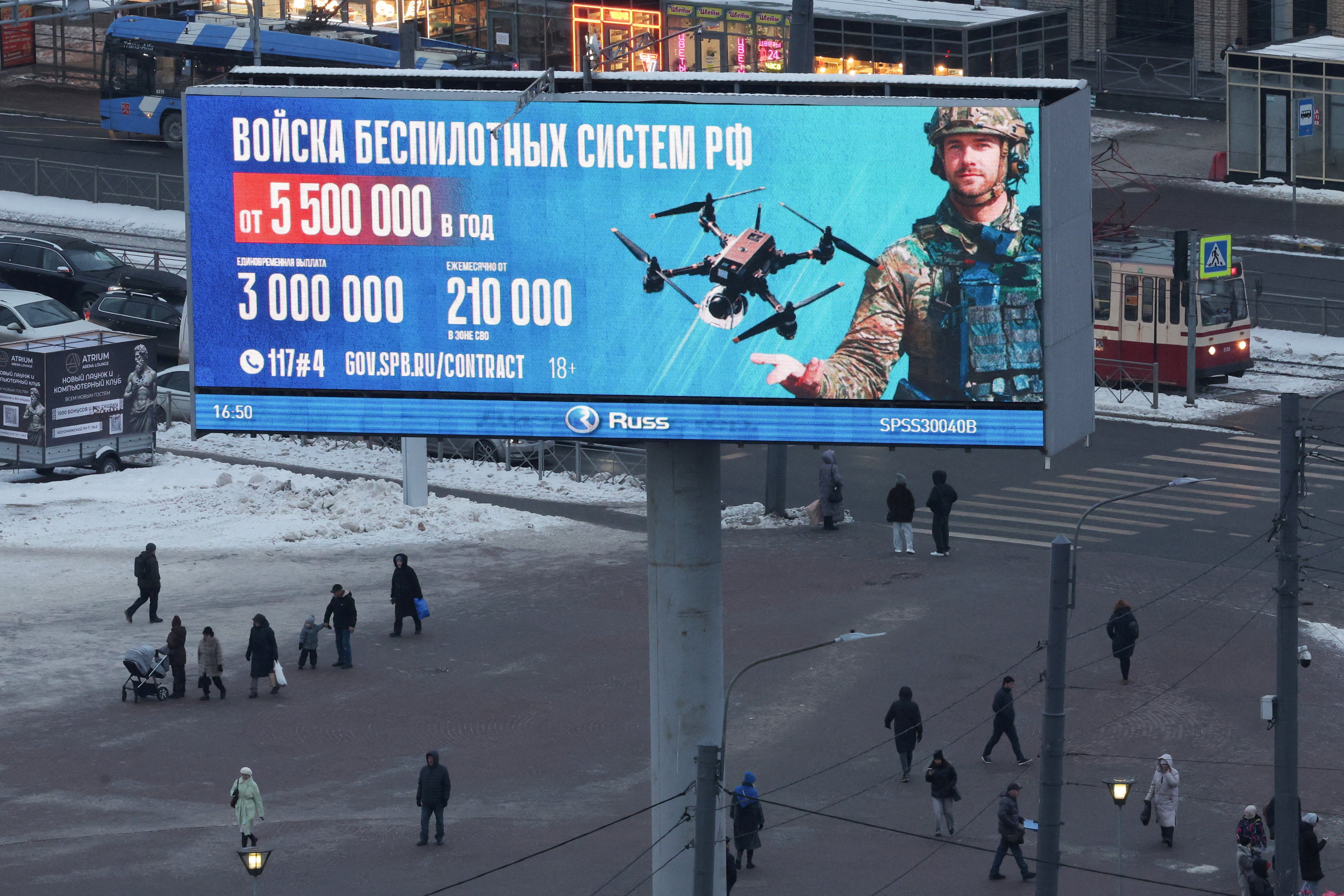 People walk under a digital screen displaying an ad promoting contract military service in the Russian army's unmanned systems forces