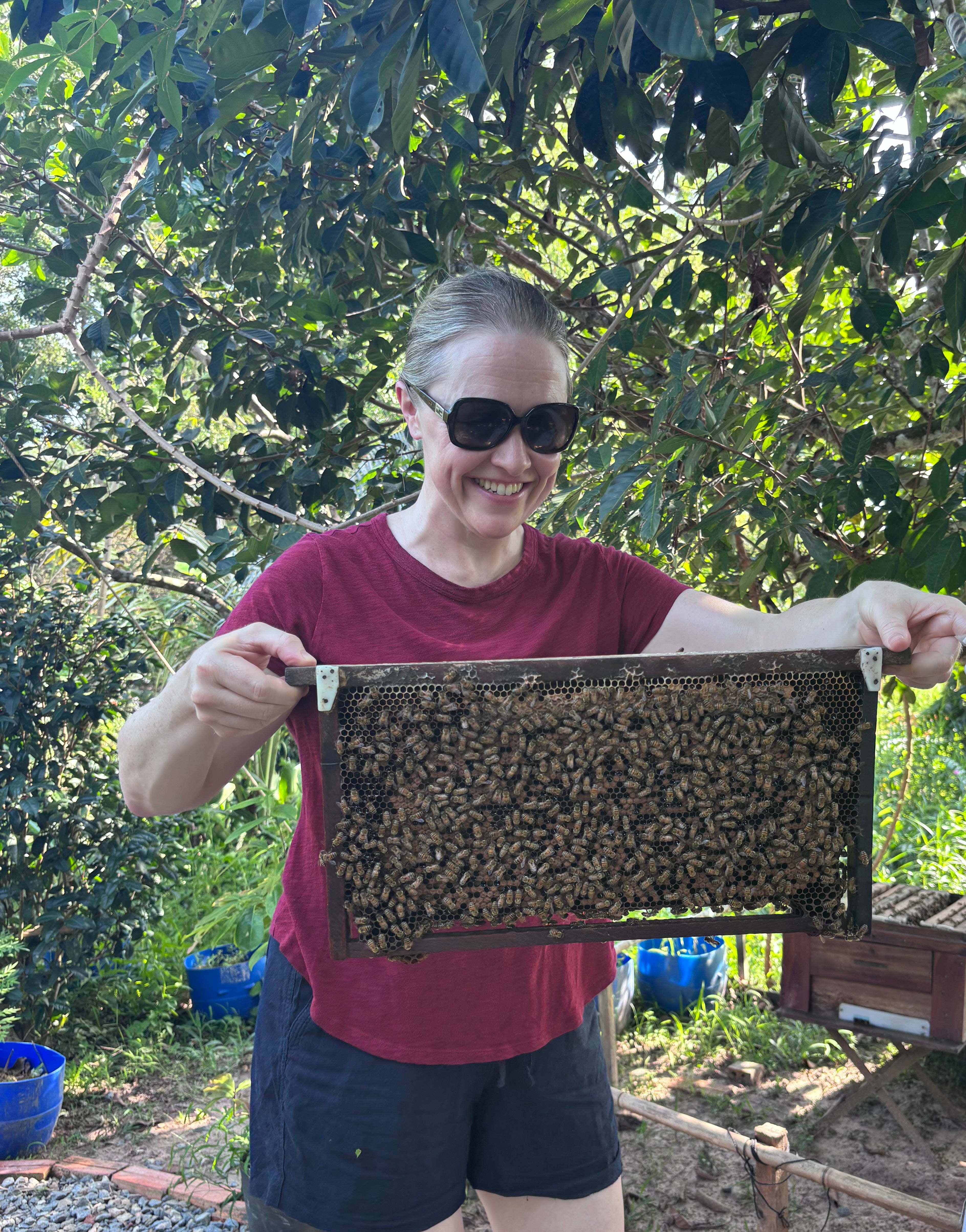 Siobhan holding a frame of bees at the honey farm
