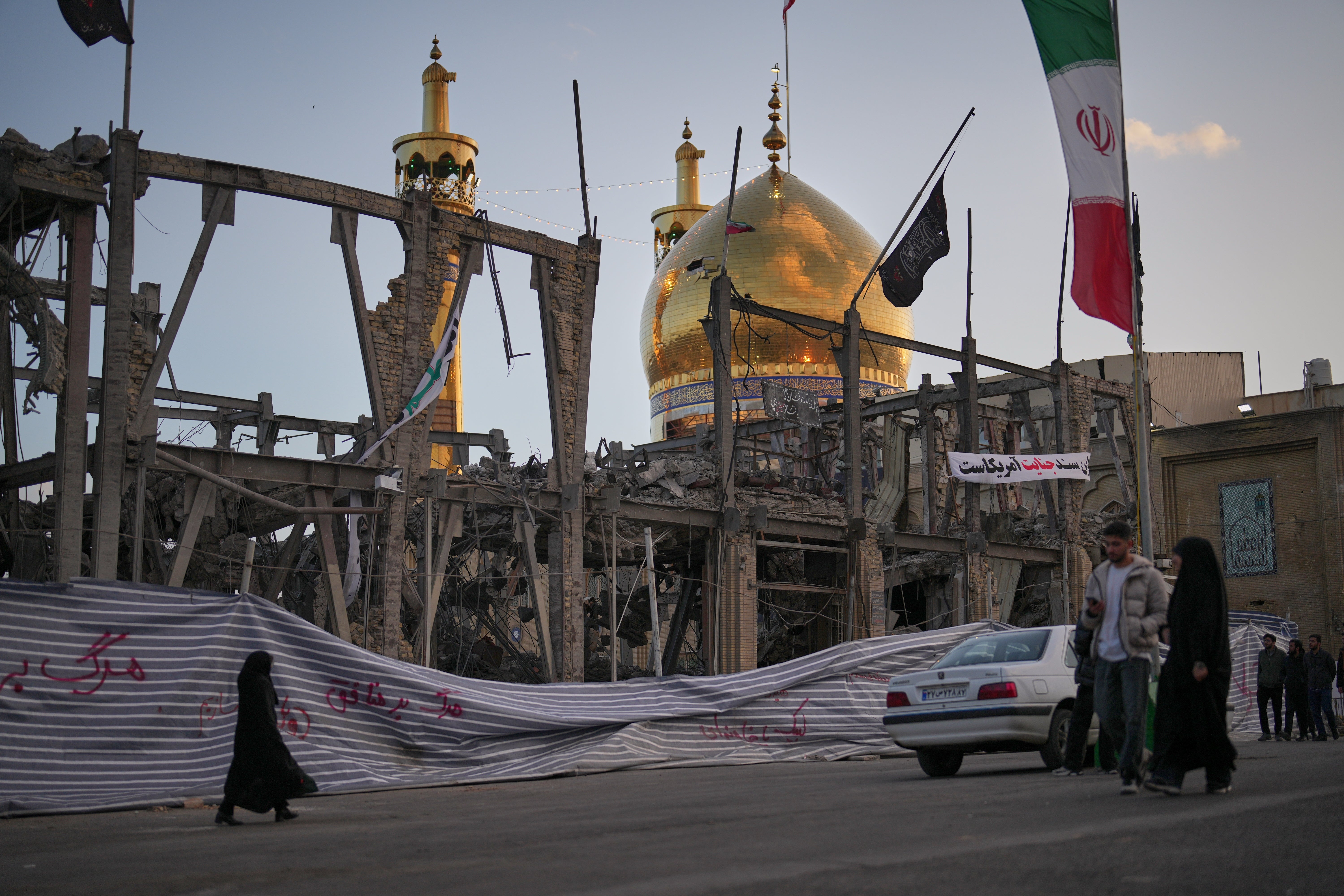 Pedestrians walk past a destroyed building within the Grand Hosseiniyeh in Zanjan, Iran