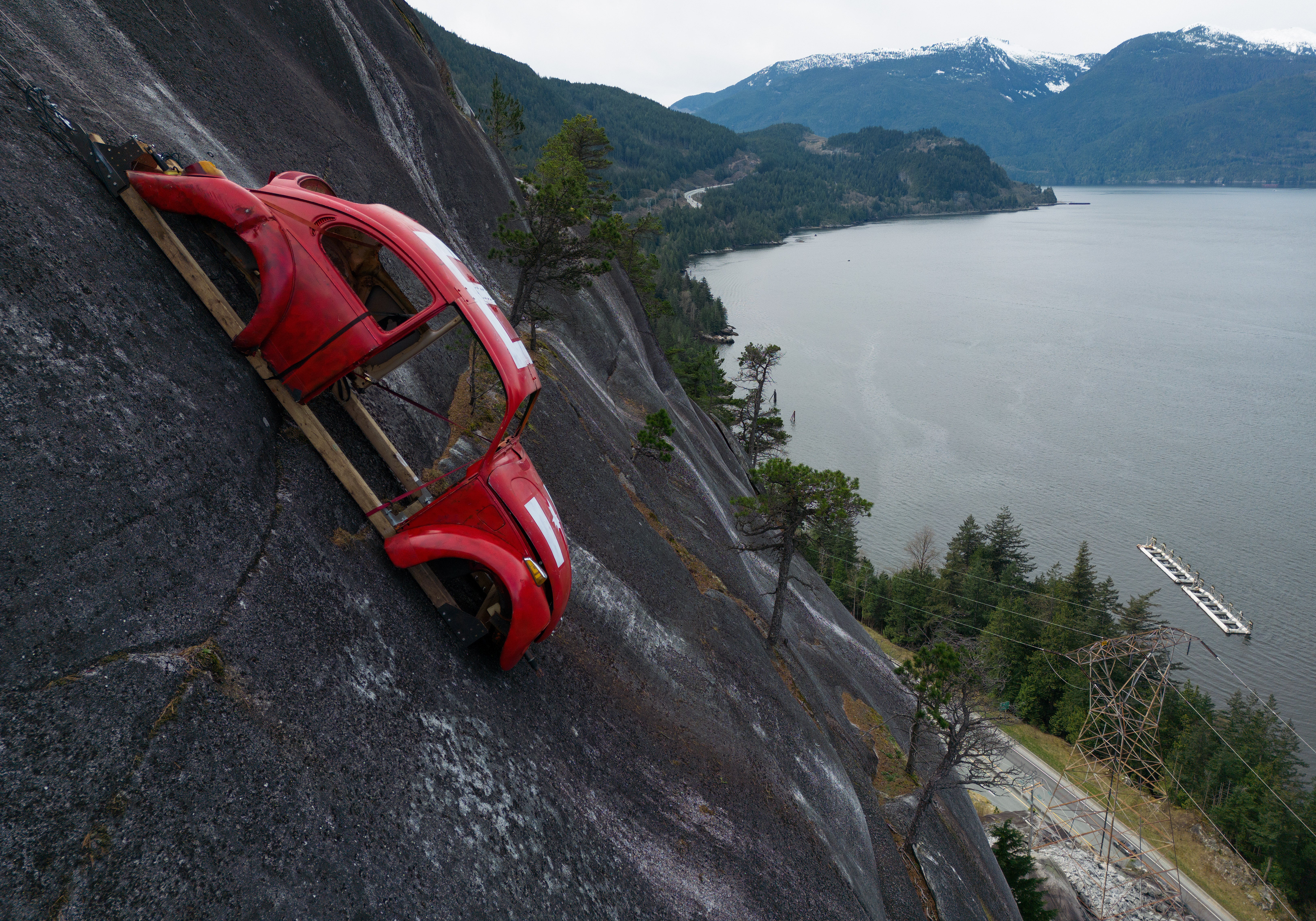 The shell of a Volkswagen Beetle hangs suspended on a cliff above the Sea-to-Sky Highway, in Squamish, British Columbia, Monday, April 6, 2026, after it appeared on the rock face last week with a large 