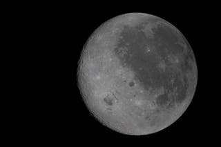 Moon's near side visible on the right, identifiable by the dark splotches that cover its surface